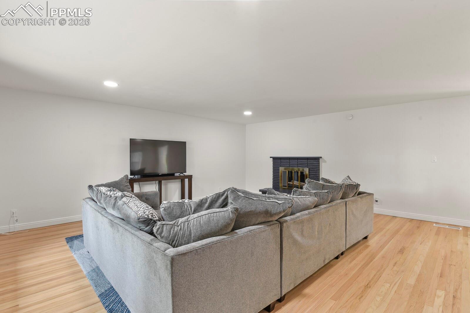 Spacious living room featuring hardwood flooring, recessed lighting and a fireplace