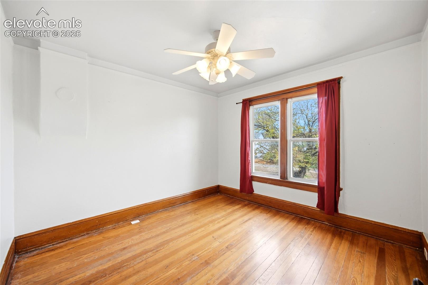 Interior room featuring wood-finish flooring, natural wood window trim, a multi-light ceiling fan, and crown molding