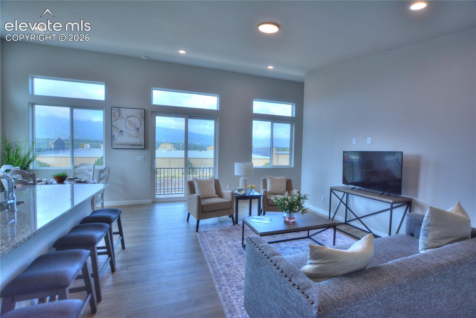 Open-concept living area featuring hardwood flooring, recessed ceiling lighting, and expansive windows with water views