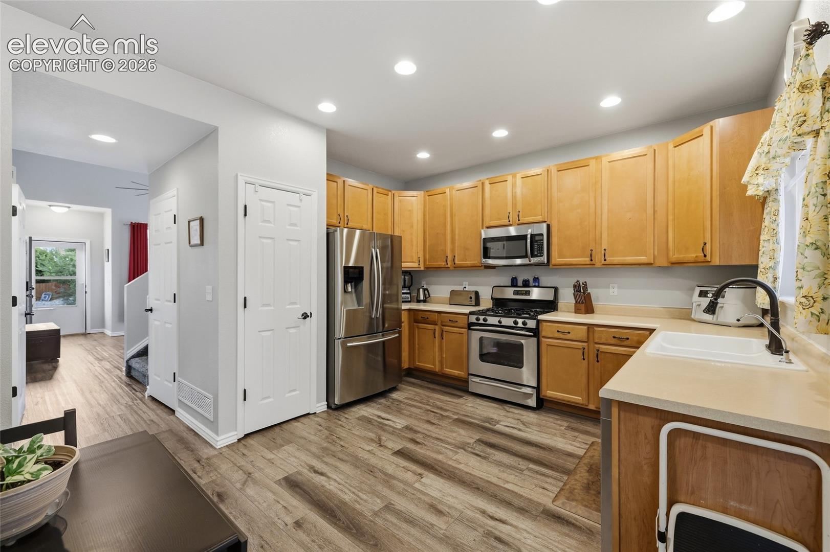 Kitchen featuring wood-finish flooring, light wood cabinetry, stainless steel appliances, and recessed lighting