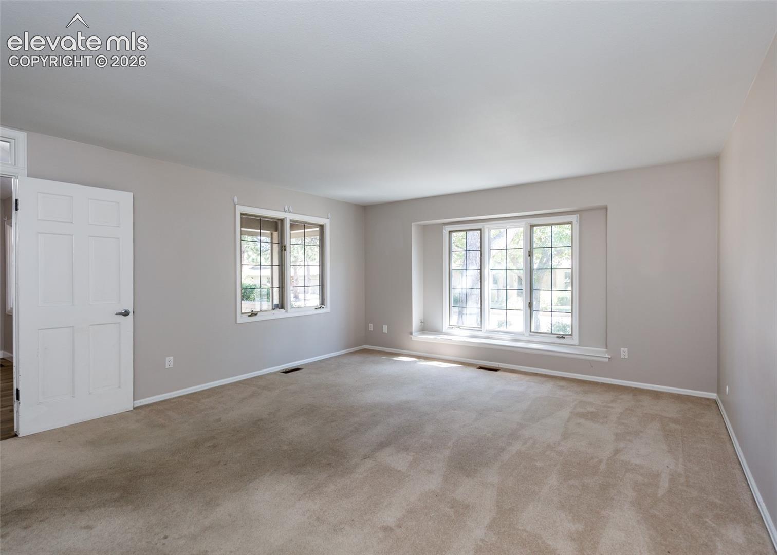 Expansive room featuring carpet flooring, painted walls, and multiple windows with white trim