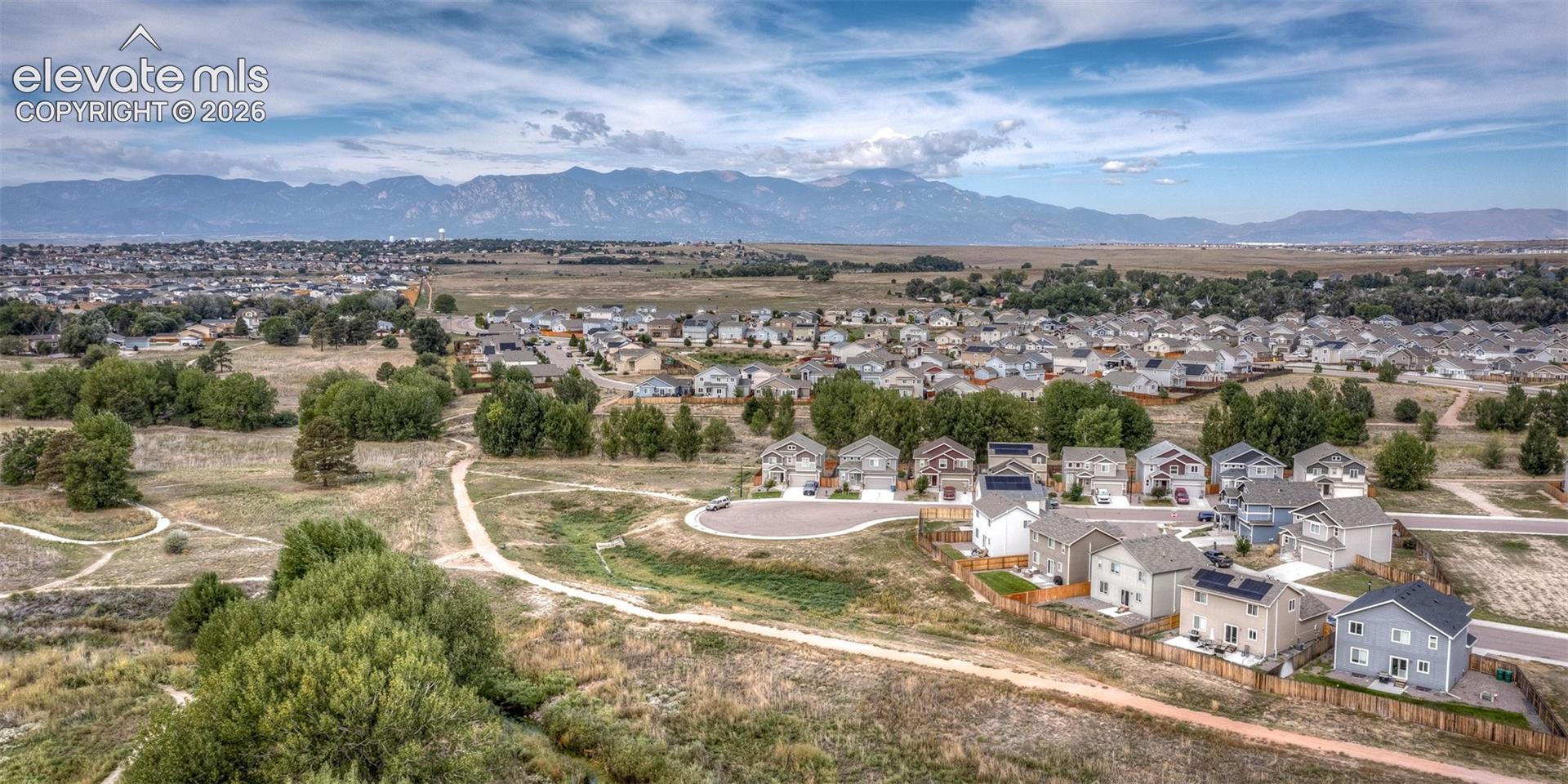 Aerial perspective featuring mountainous horizon backdrops, open space surrounding the property, and nearby walking trails