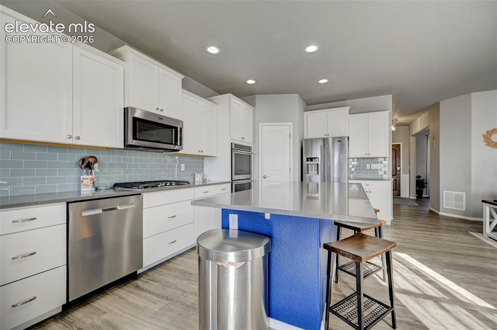 Modern kitchen featuring a central island with a contrasting blue base, light-toned countertops, and white cabinetry