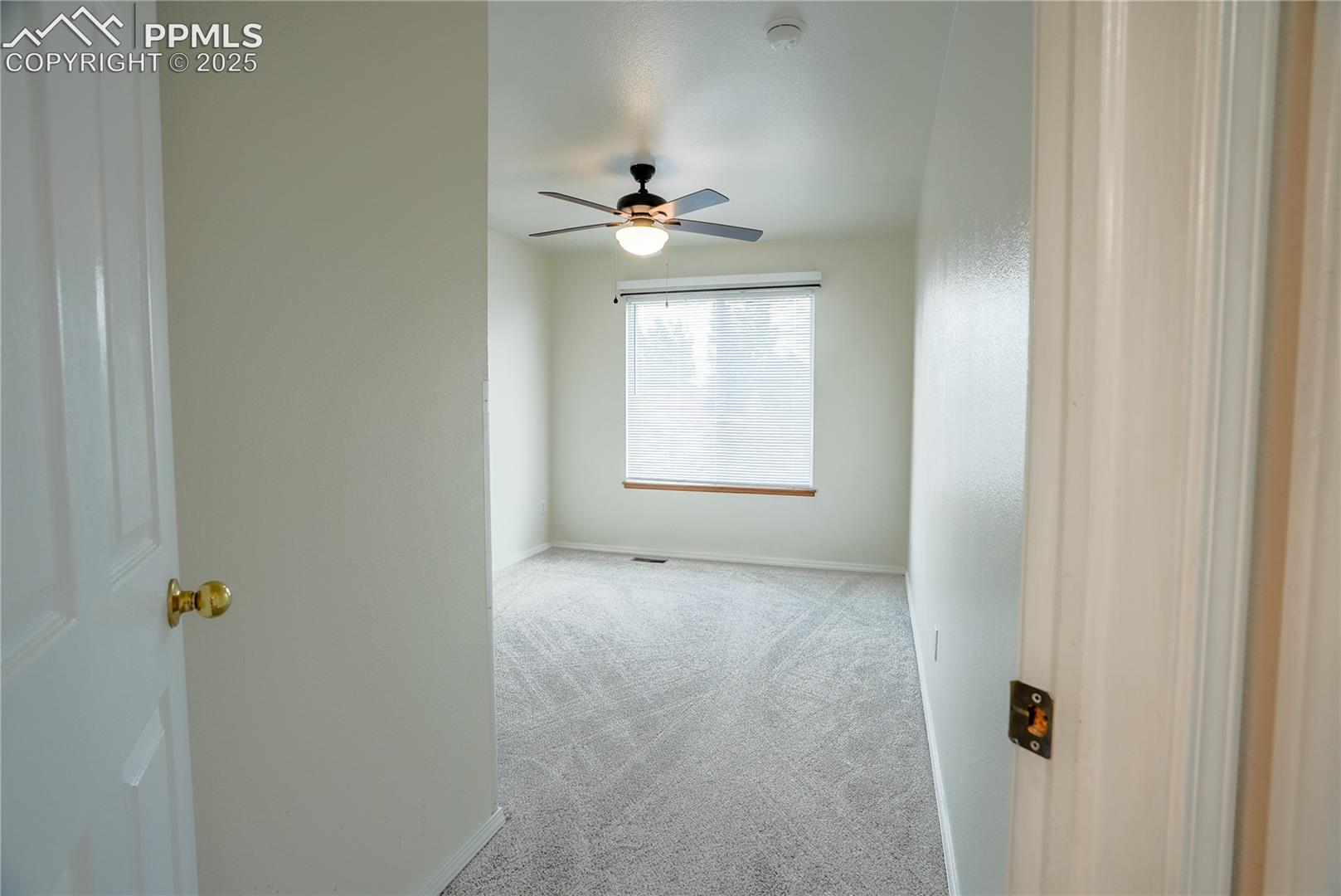 Carpeted spare room with baseboards and ceiling fan