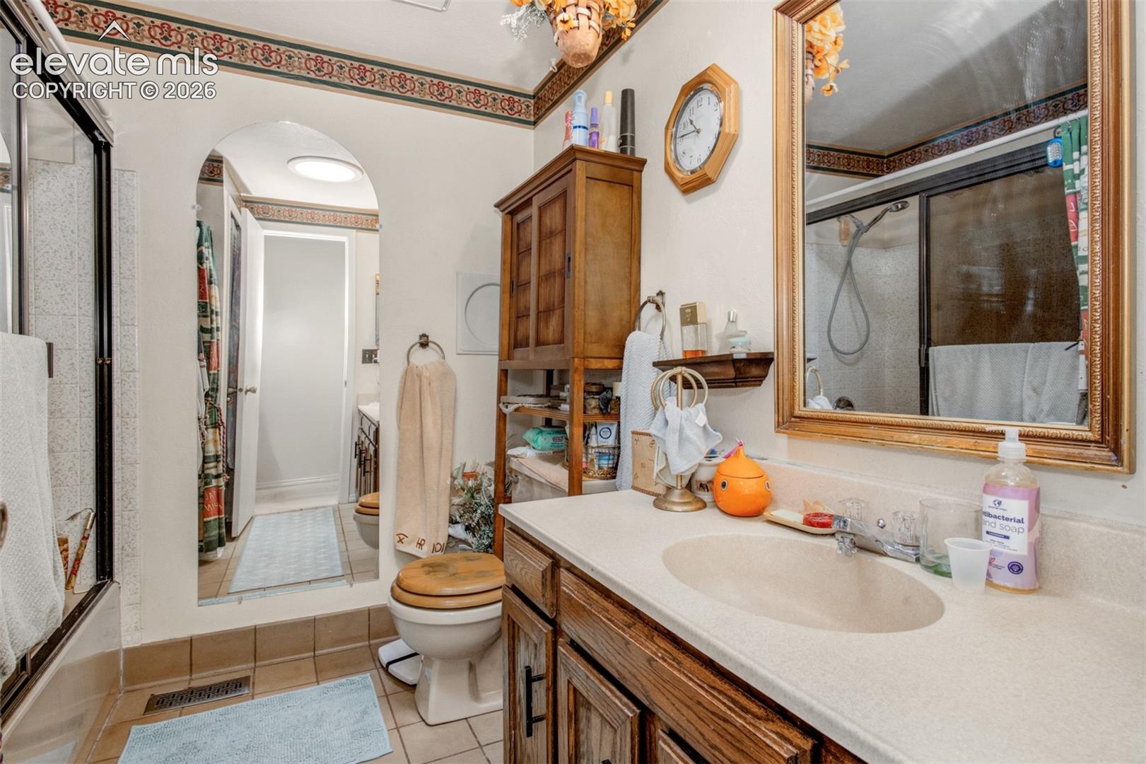 Bathroom featuring a vanity with an integrated sink, framed mirror, and a built-in shower with a glass enclosure
