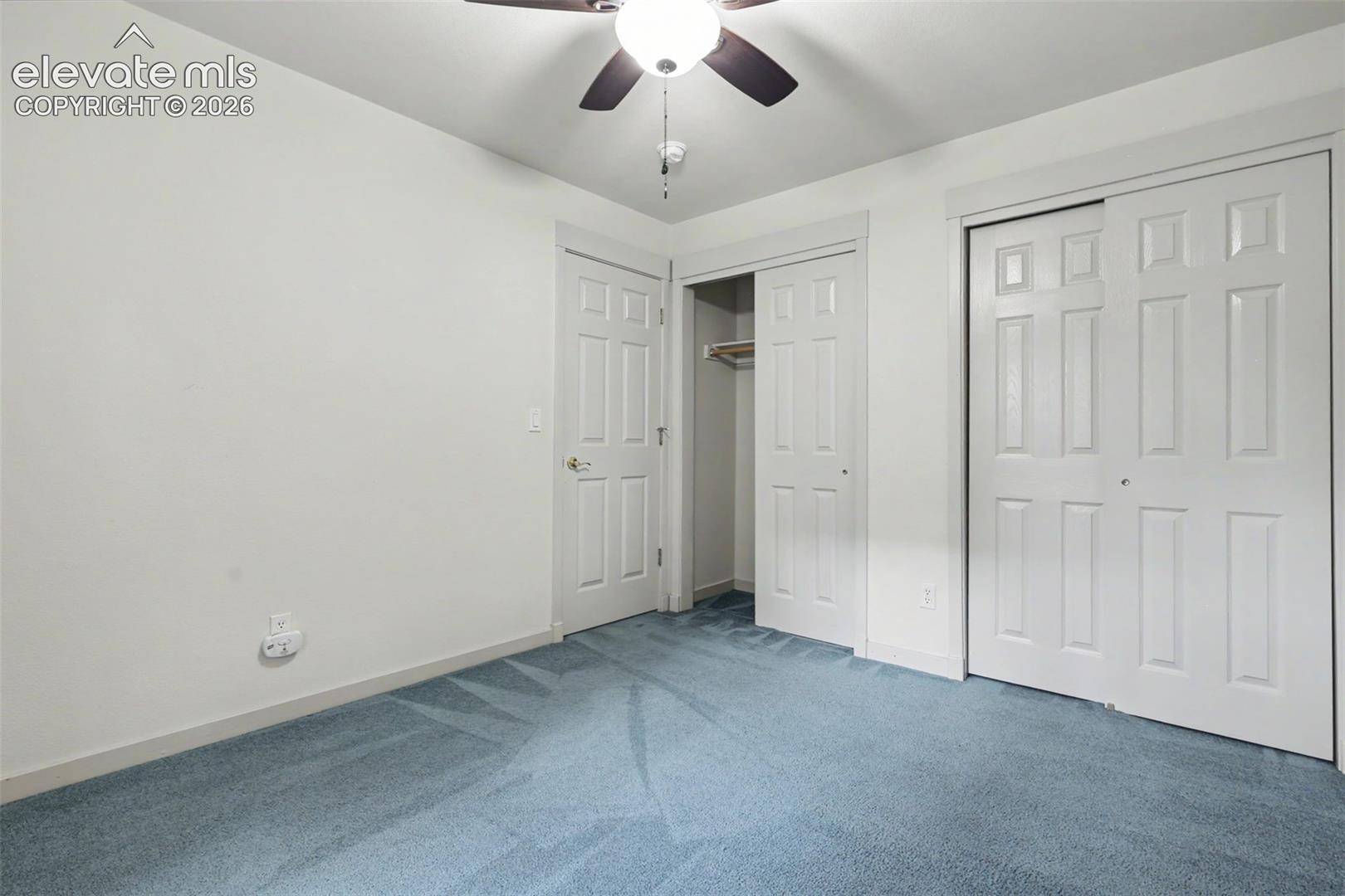 Bedroom featuring light blue carpeting, white walls, and a ceiling fan with integrated lighting