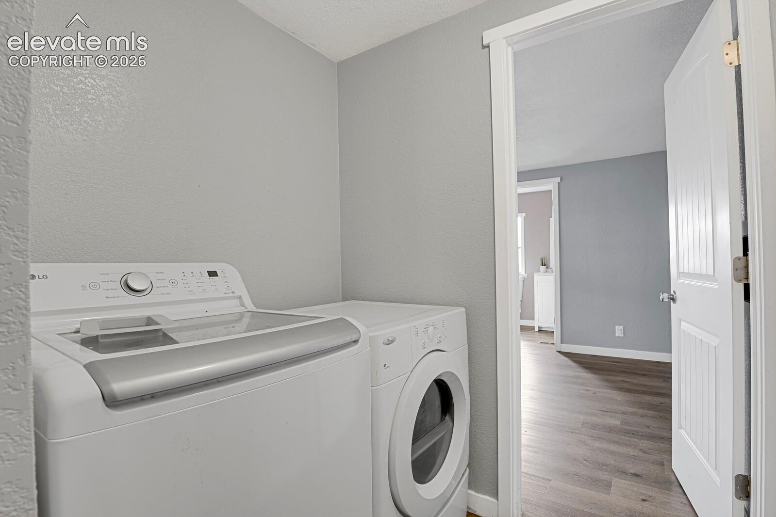 Dedicated laundry area featuring neutral wall paint, wood-finish flooring, and a solid-core interior door with a paneled design
