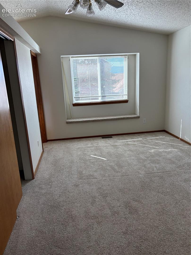 Vaulted ceilings, built-in window seat, neutral carpeting, and multi-light ceiling fixture