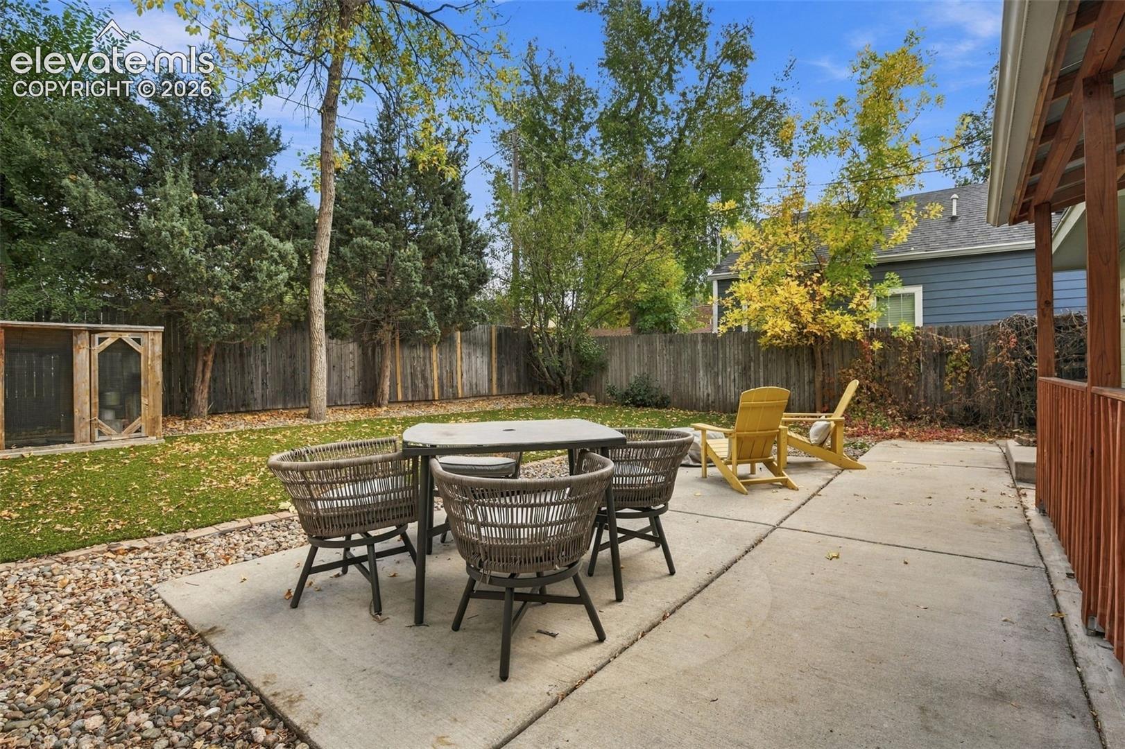 Backyard featuring a concrete patio, wood-slat perimeter fencing, stone ground cover, and a detached wooden storage structure