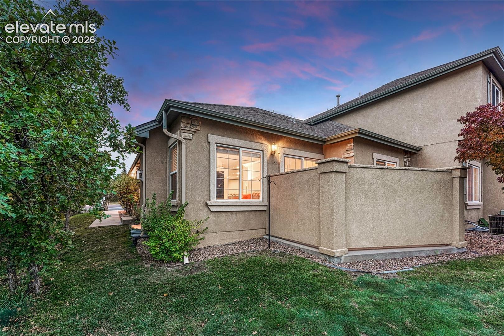 Rear exterior view showcasing the sturdy stucco privacy wall enclosing the patio and lush surrounding green lawn
