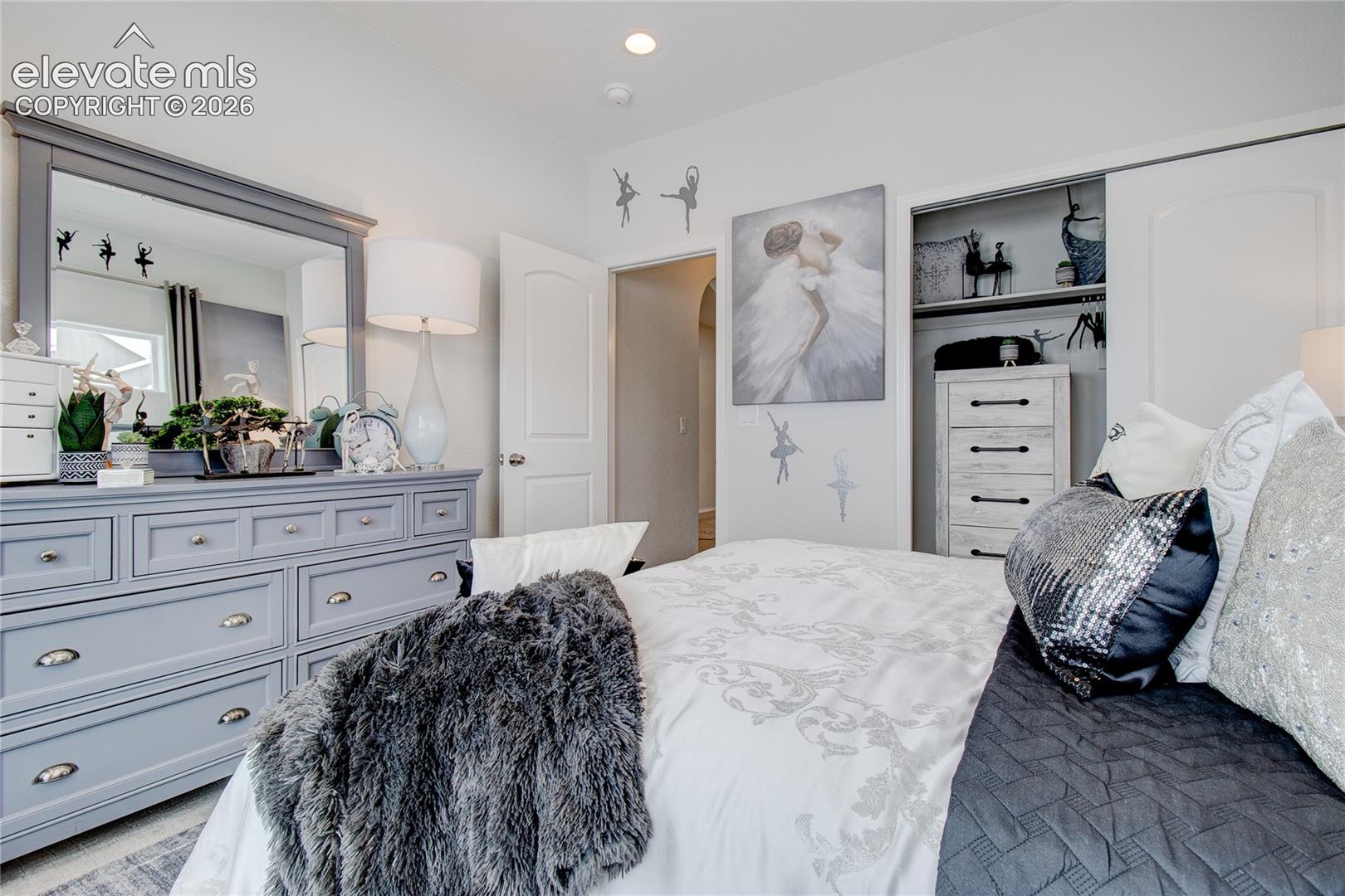Neutral-toned bedroom featuring a recessed closet with sliding doors, arched interior door, and recessed ceiling lighting