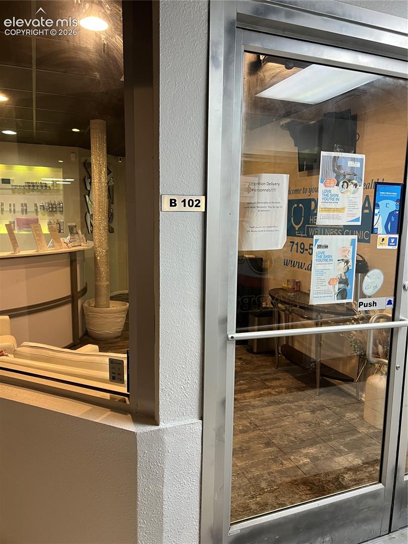 Commercial unit entrance featuring a full-glass door with a metallic frame, tiled flooring, and a curved built-in reception desk