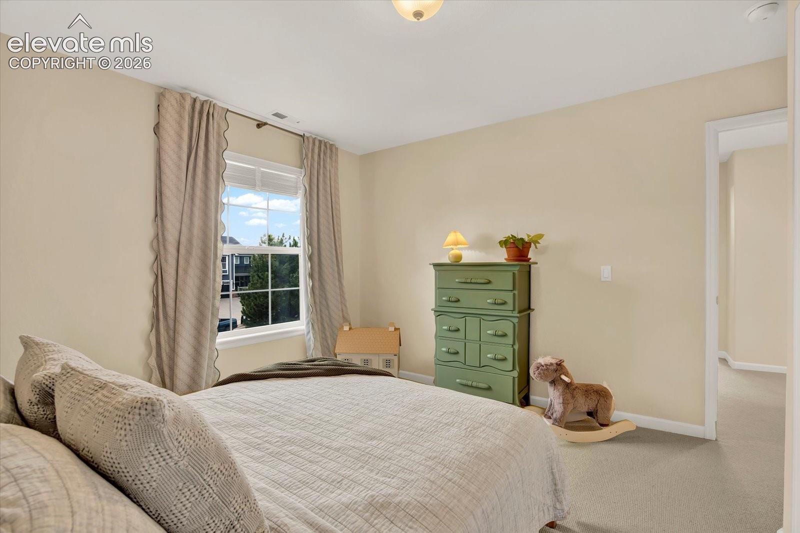 Neutral-toned room featuring wall-to-wall carpeting, a multi-pane window, and a flush-mount ceiling light fixture