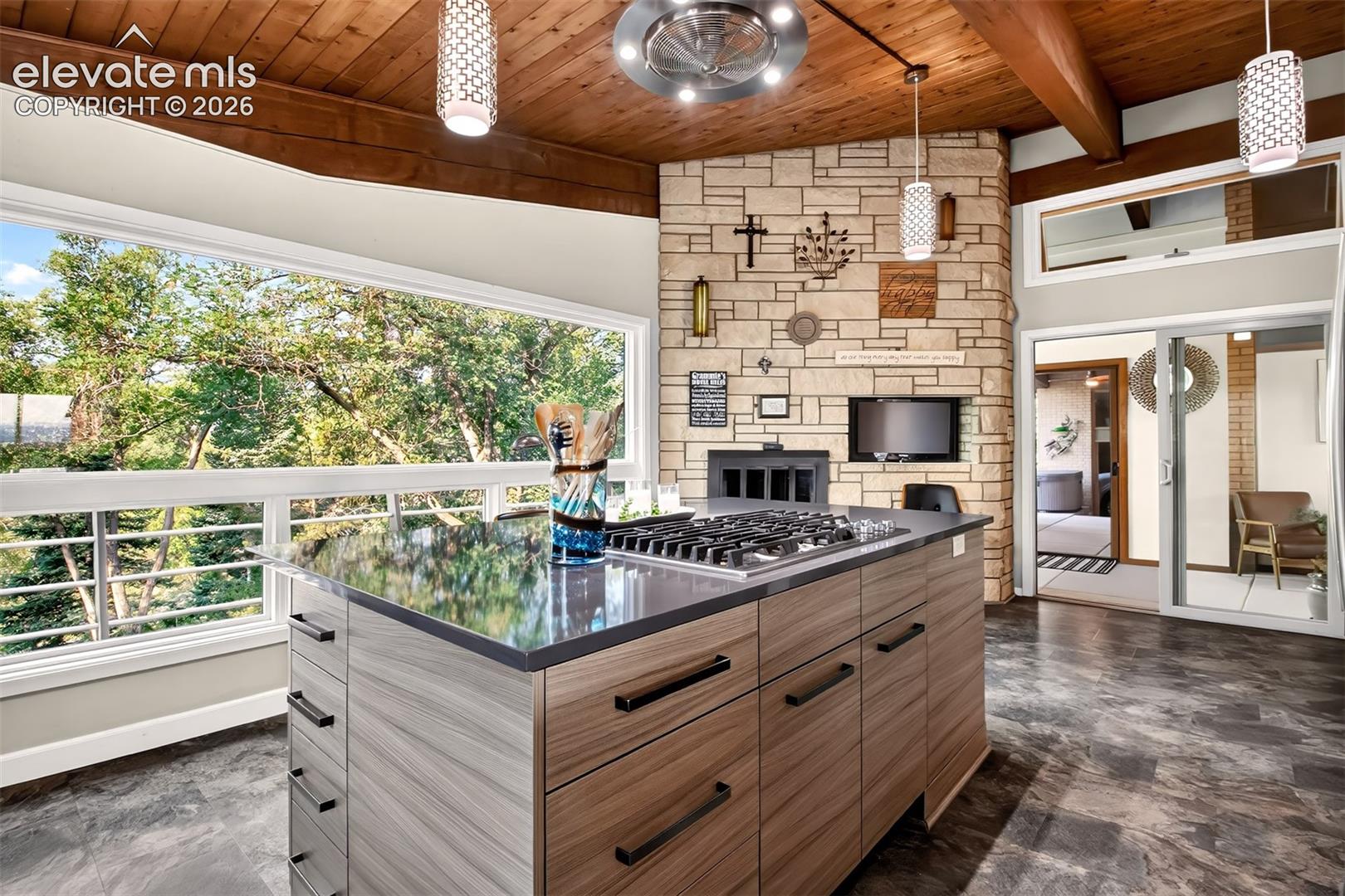 Another view of the kitchen showing the gas 5 burner downdraft cooktop and looking into the sun room.