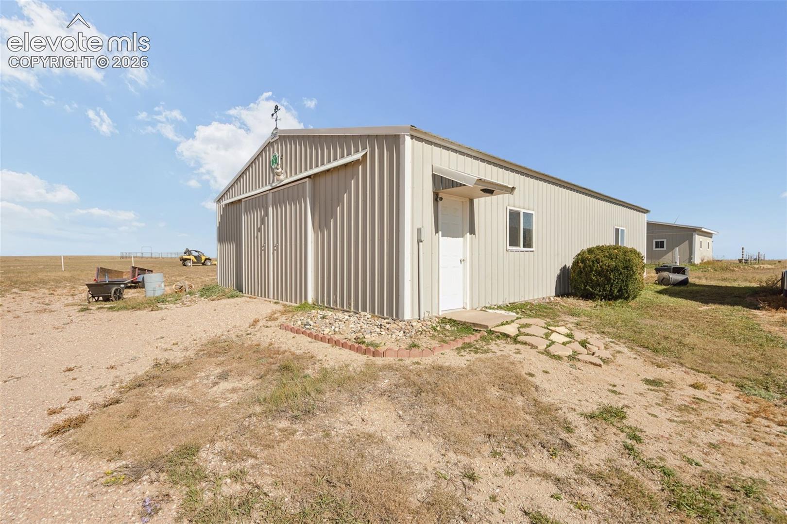 Detached metal-sided structure featuring a gabled roof, sliding entry door, and stone-accented exterior foundation
