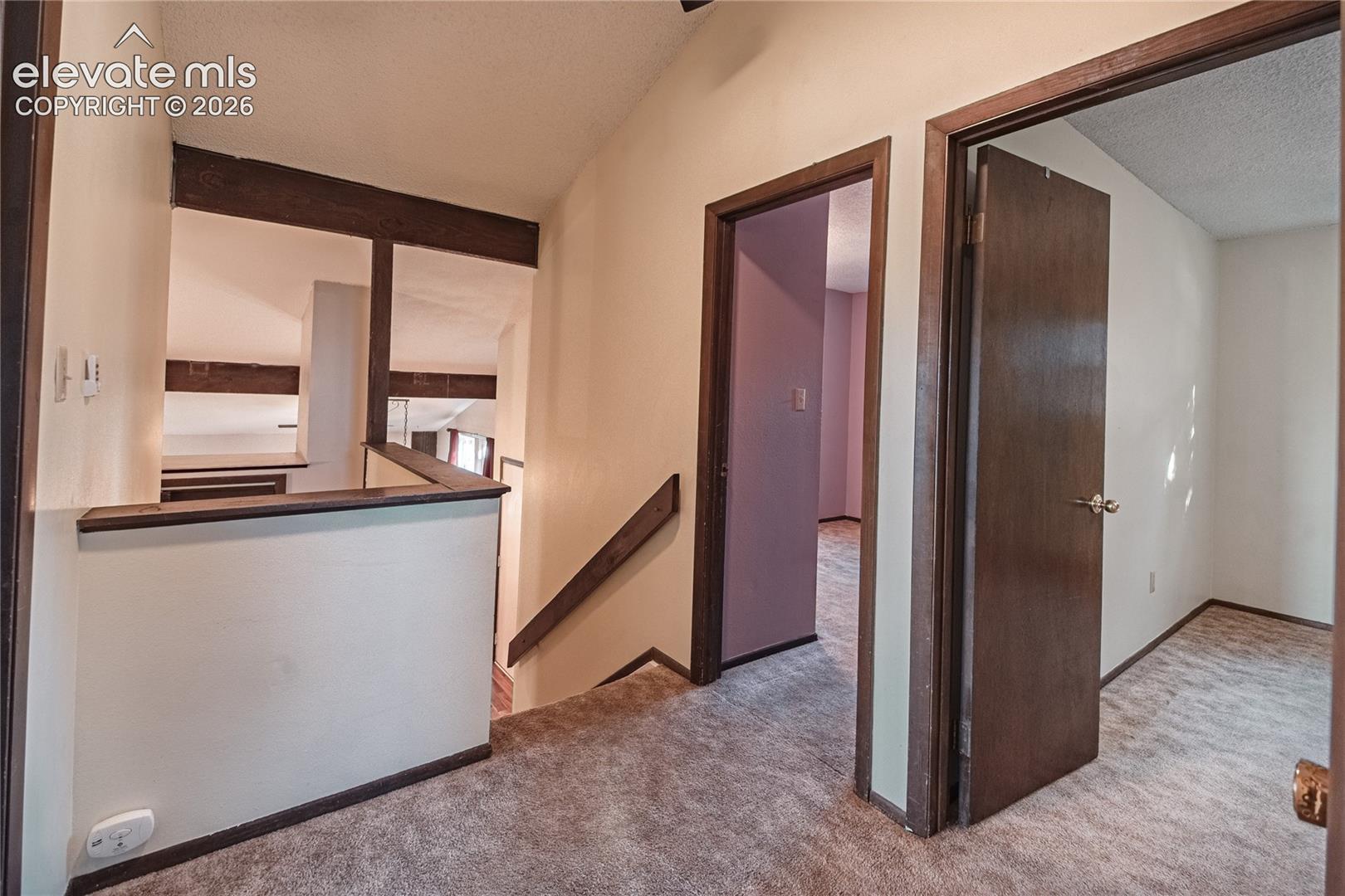 Hallway featuring exposed wood beam accents, solid-core wood doors, and textured wall finishes