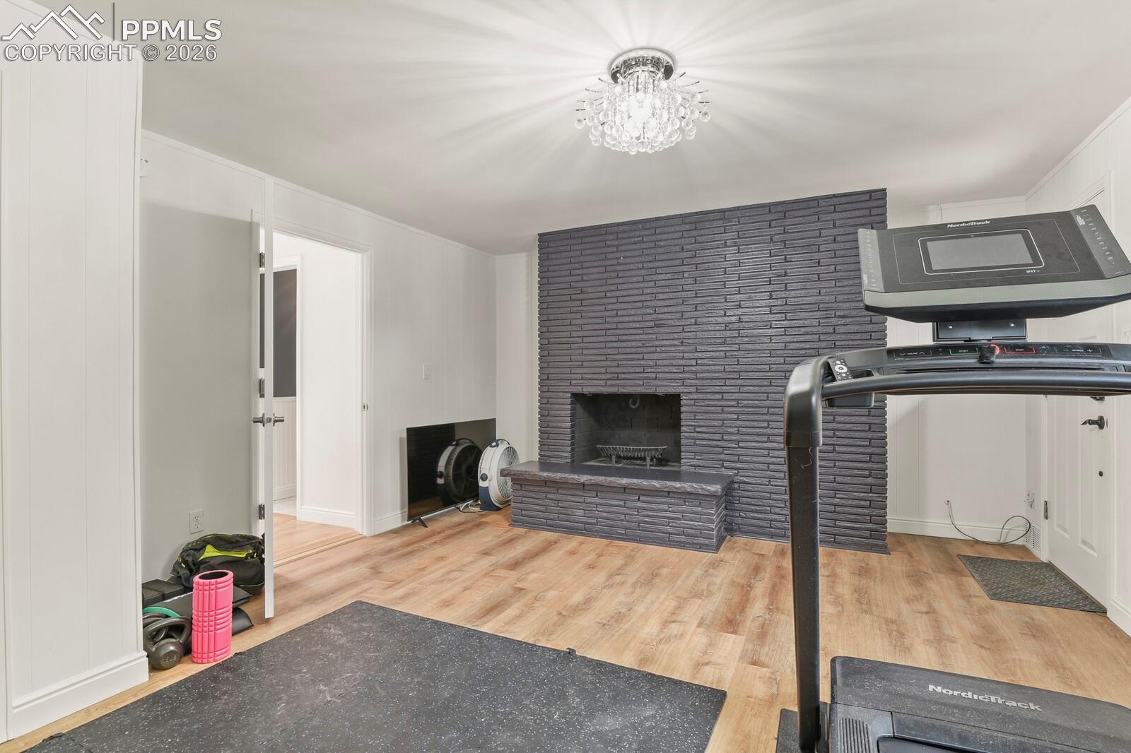 3rd bedroom on main level with a fireplace, exterior door to outside, hardwood flooring and a  chandelier