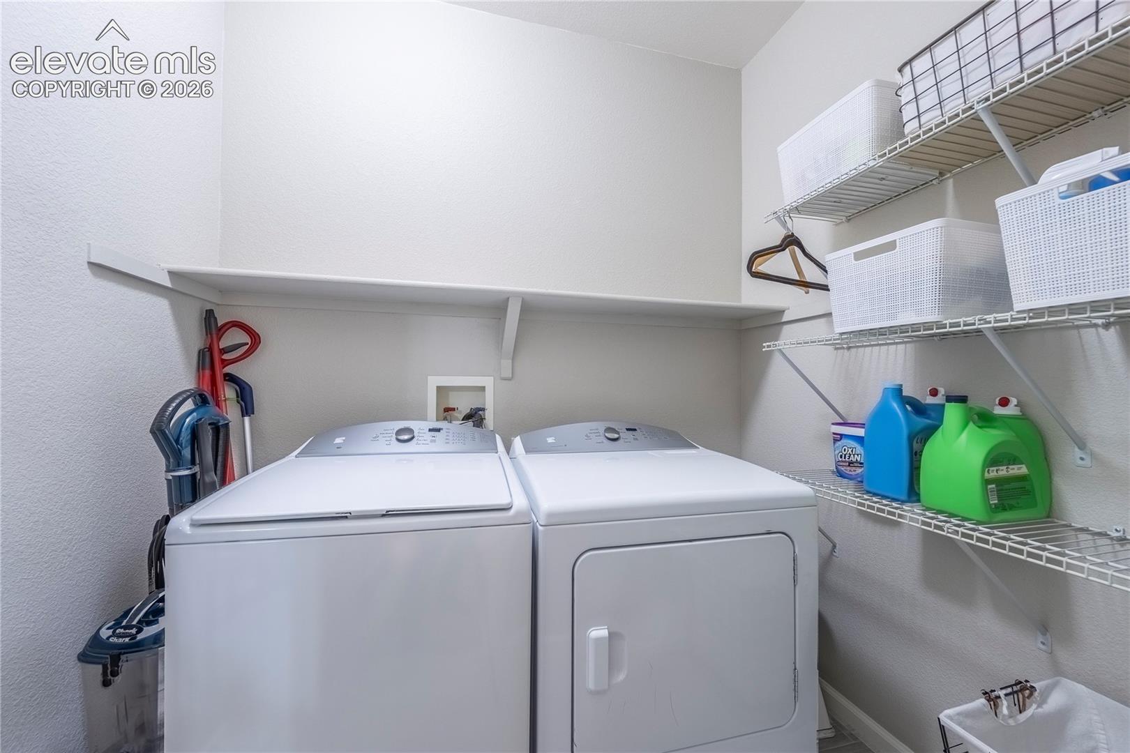 Laundry area featuring upper wall-mounted shelving and integrated wire storage racking