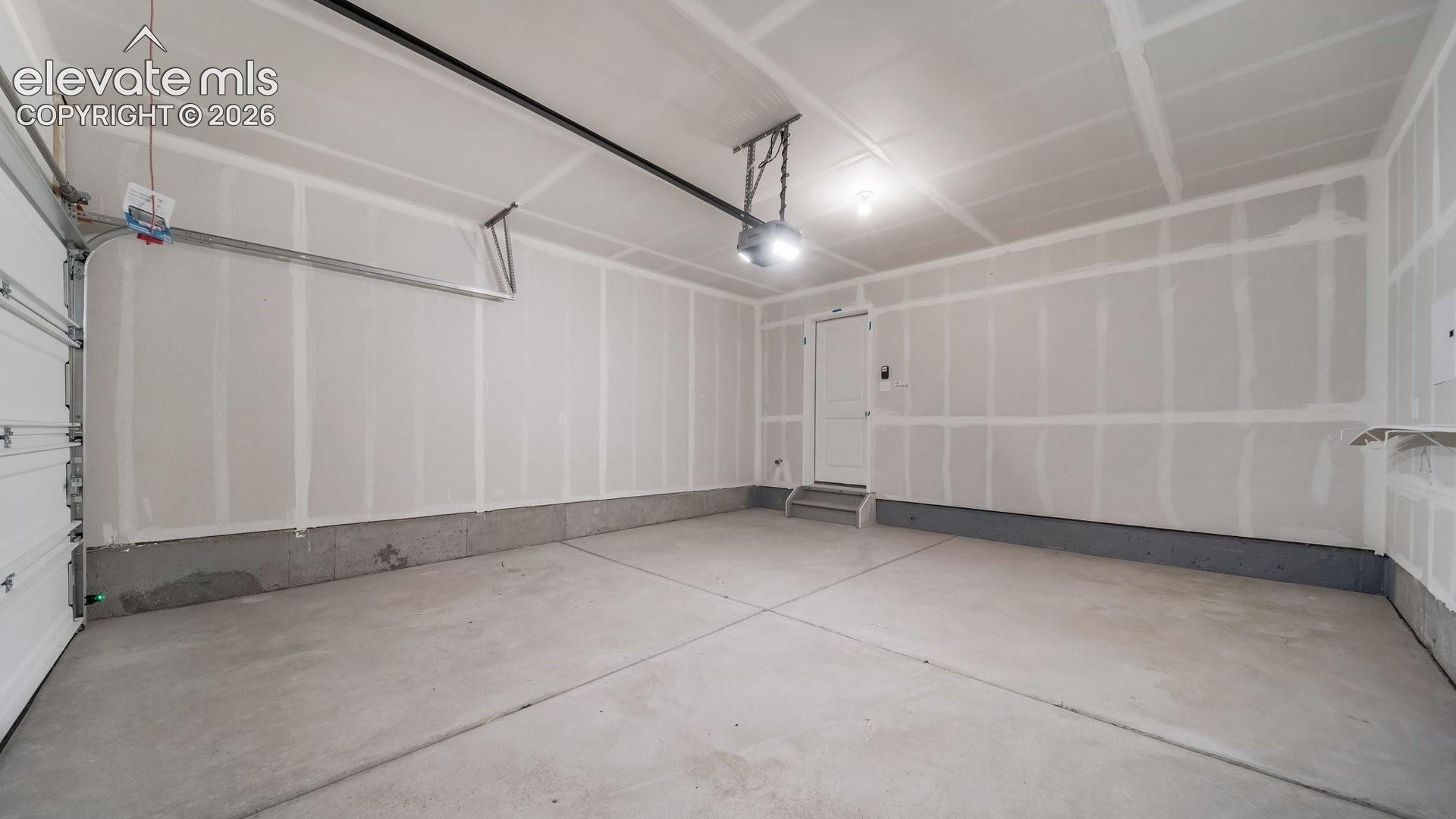 Two-car garage featuring a concrete floor, finished drywall, an automatic door opener, and a single-panel interior entry door
*photos of a model home*