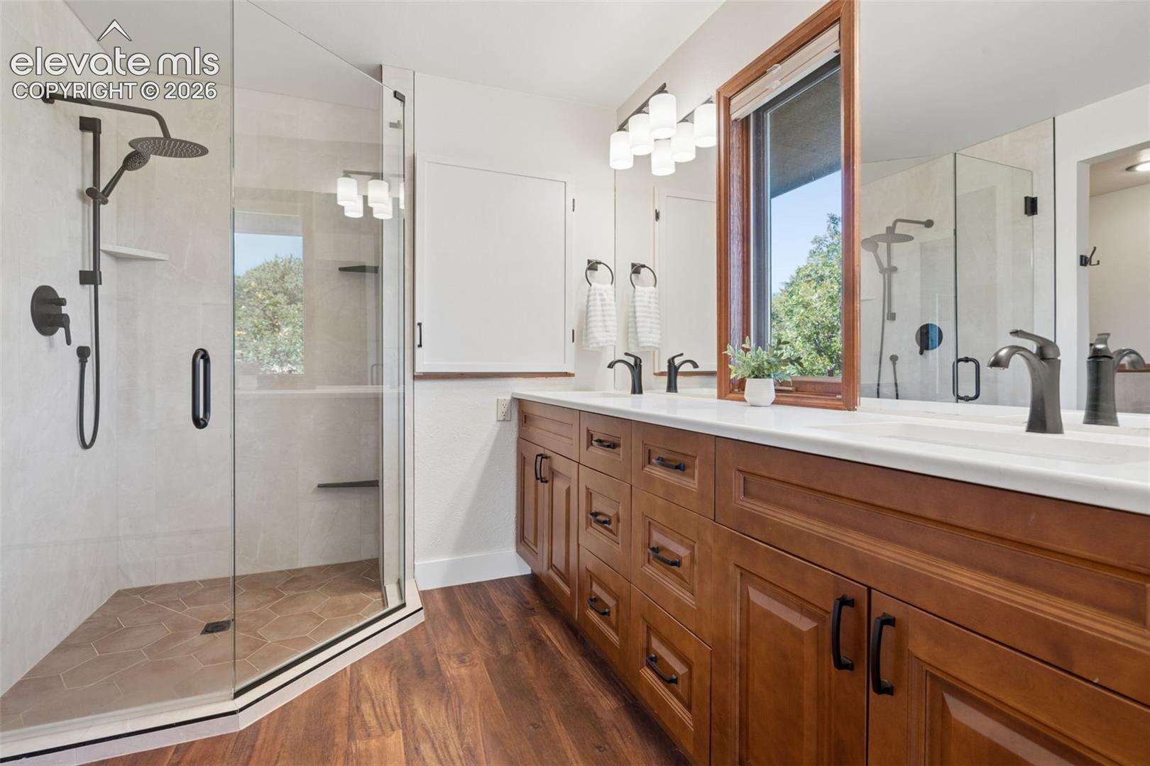 Glass-enclosed shower with a rainfall showerhead, integrated shelving, and a tiled floor