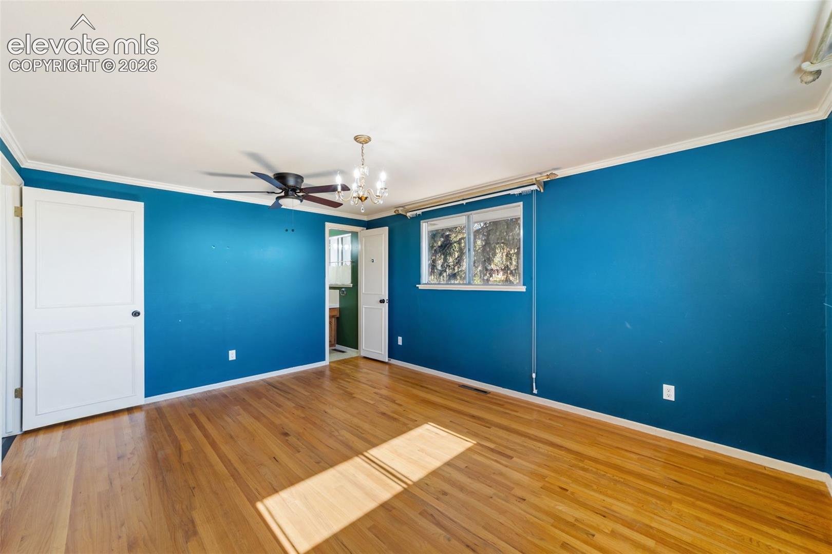 Spacious room featuring wood-finish flooring, a ceiling fan, and a chandelier
