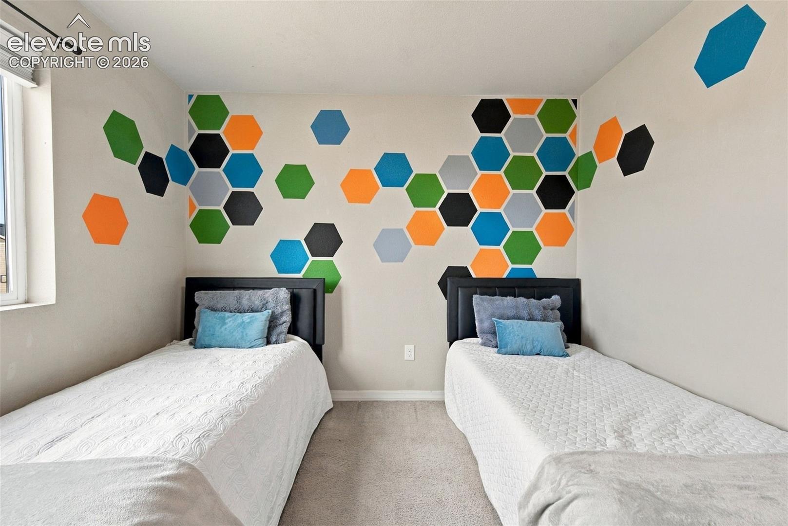 Bedroom featuring neutral carpeting and a geometric hexagon wall pattern