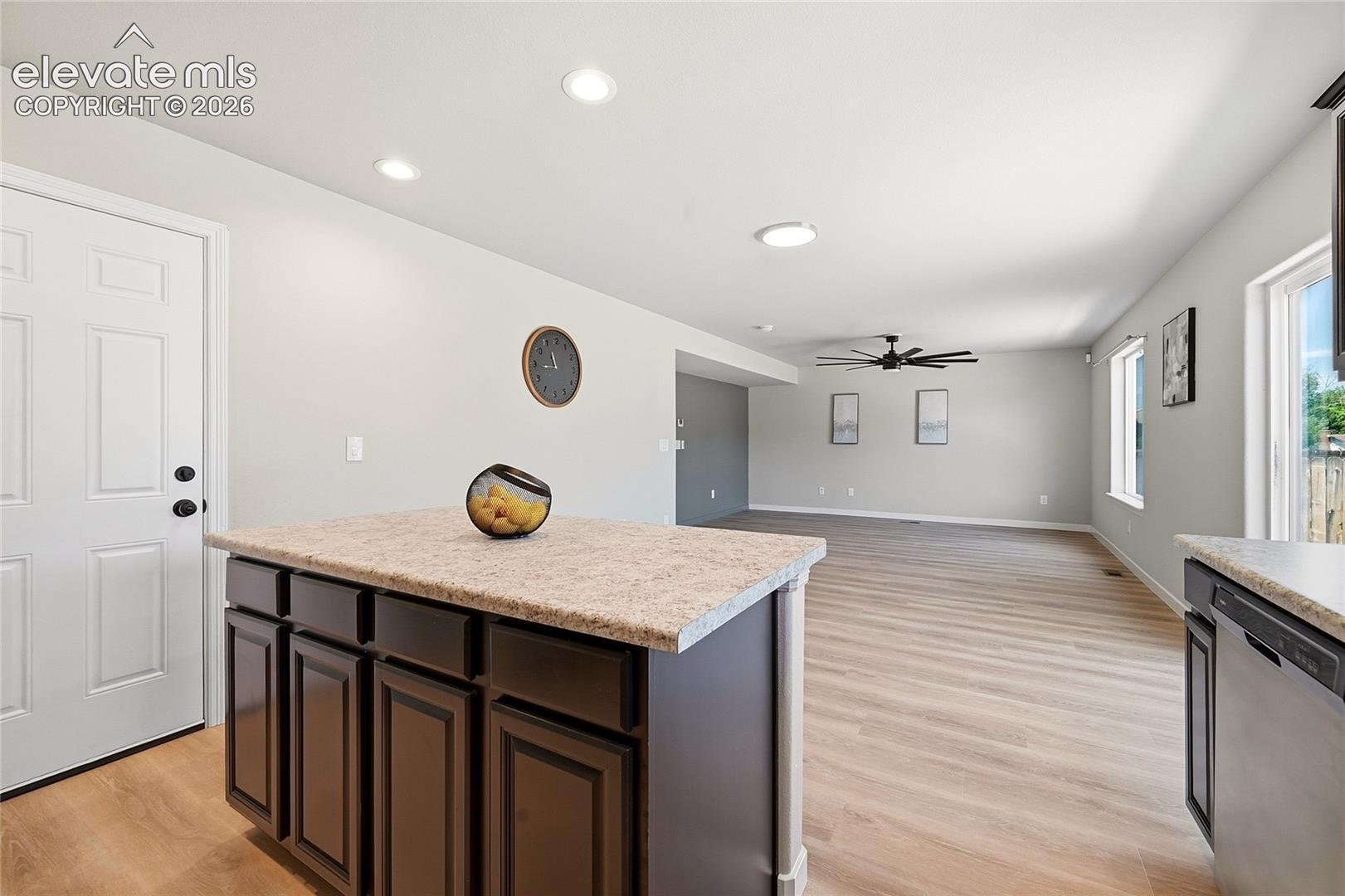 Open-concept living space featuring wood-finish flooring, recessed lighting, a ceiling fan, and ample natural light from multiple windows