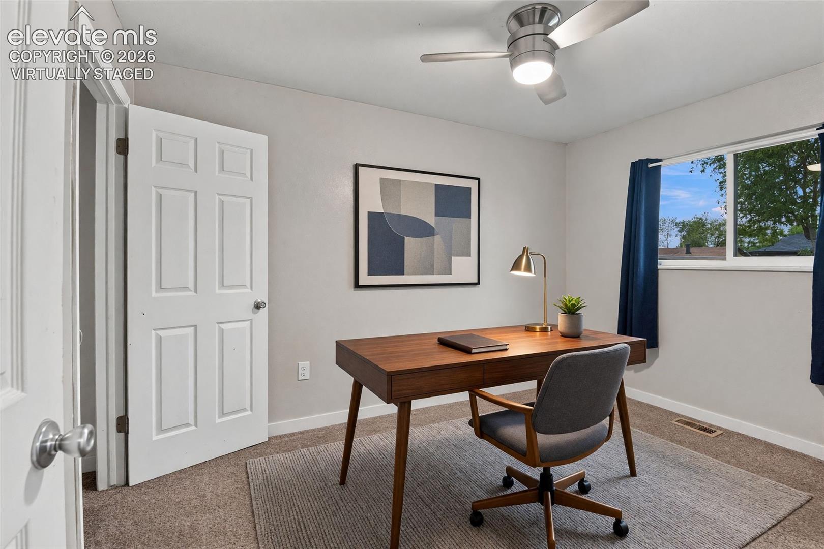 Main level secondary bedroom or home office with a ceiling fan with integrated lighting *virtually staged
