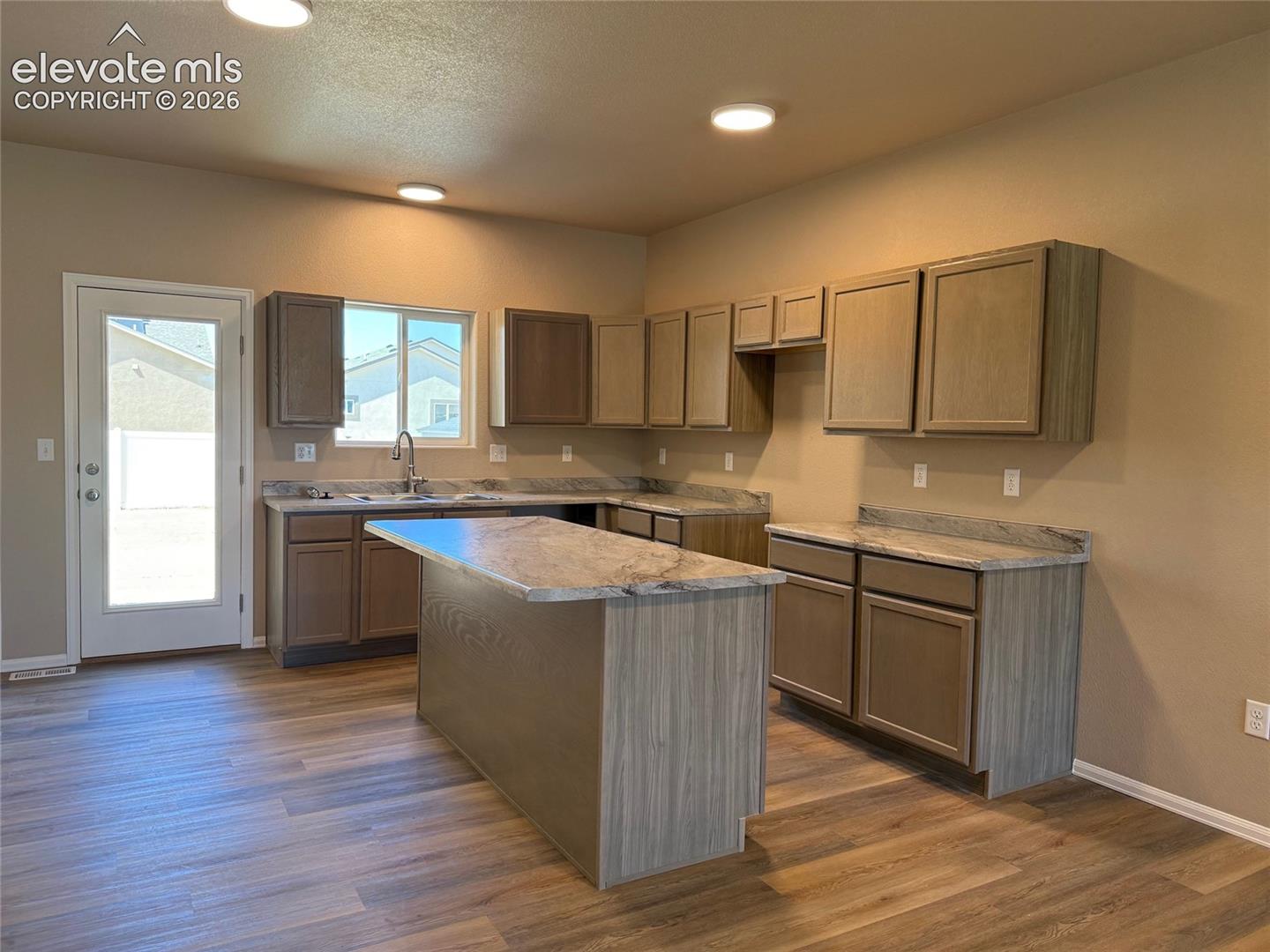 Kitchen featuring wood-finish flooring, recessed lighting, wood cabinetry, stone-finish countertops, and a central island