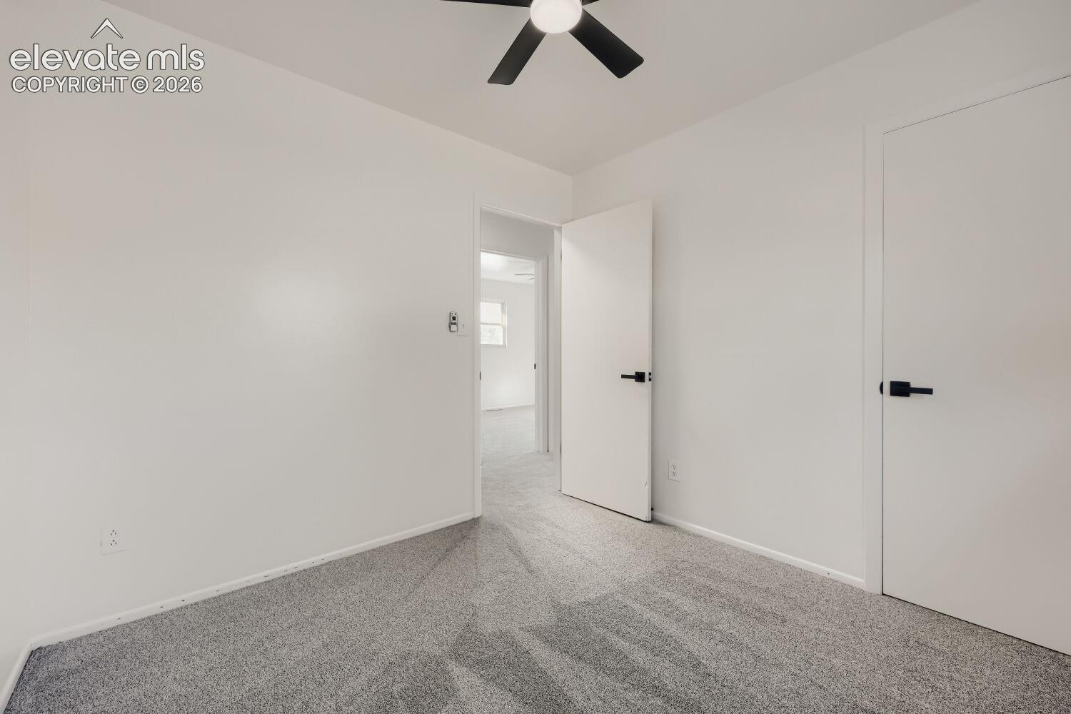 Carpeted flooring, ceiling fan, and white doors with matte black hardware