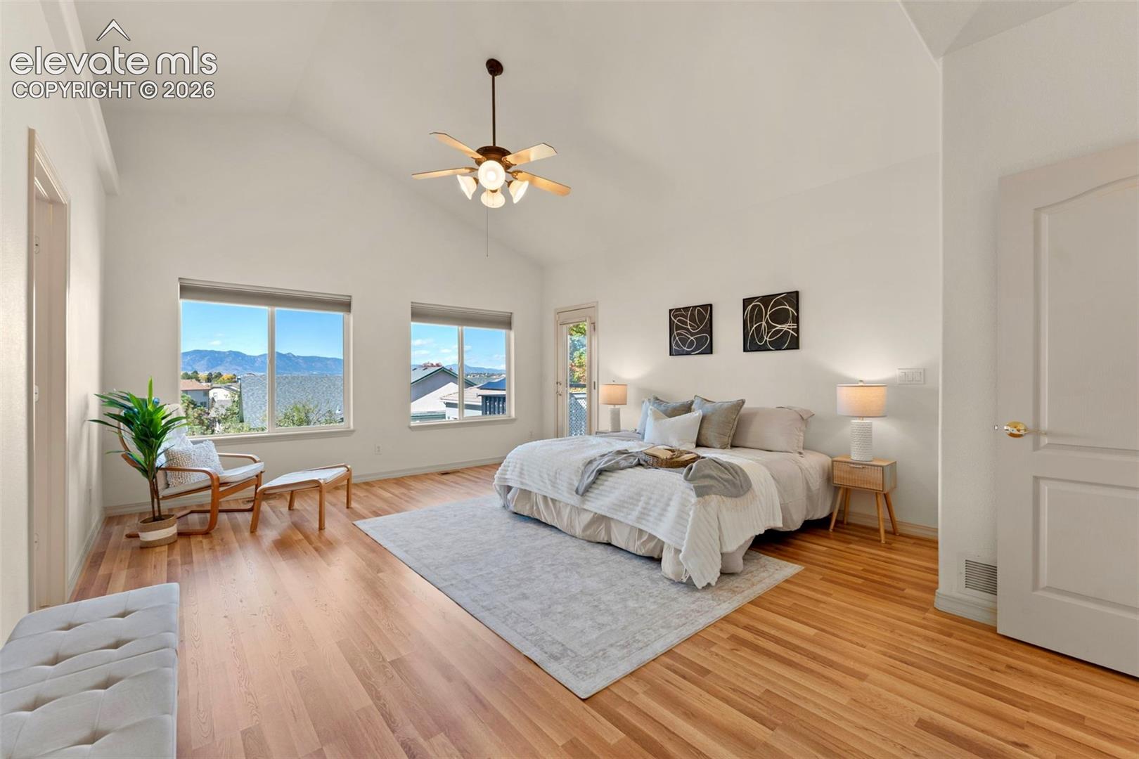 Vaulted ceilings, wood-finish flooring, mountain backdrop, and multi-light ceiling fan