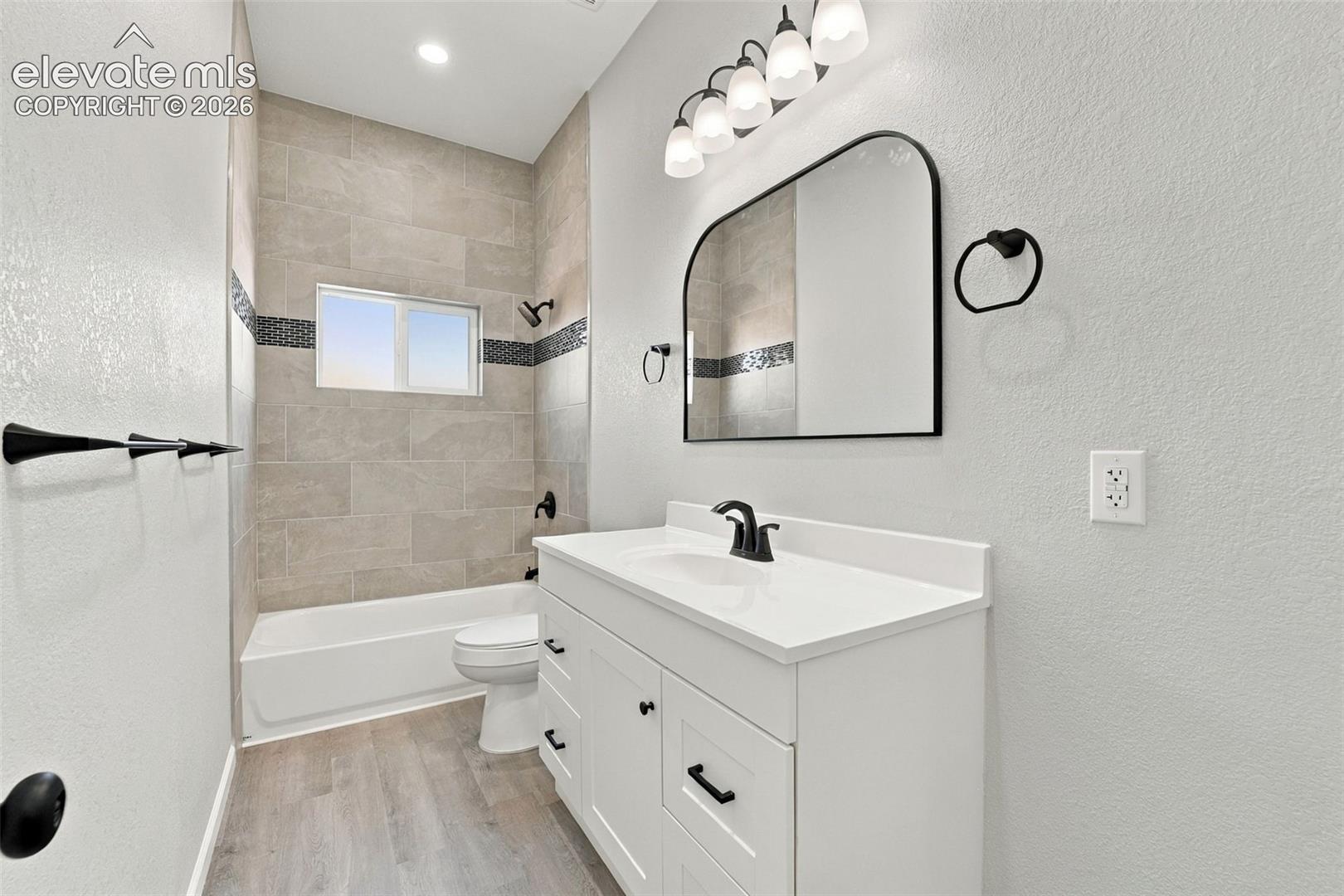 White vanity with a single basin sink, matte black faucet, and arched mirror