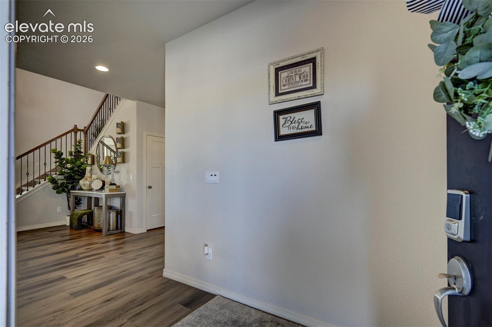 Entryway featuring wood-finish flooring, a contemporary staircase with wrought iron balusters, and a solid core interior door