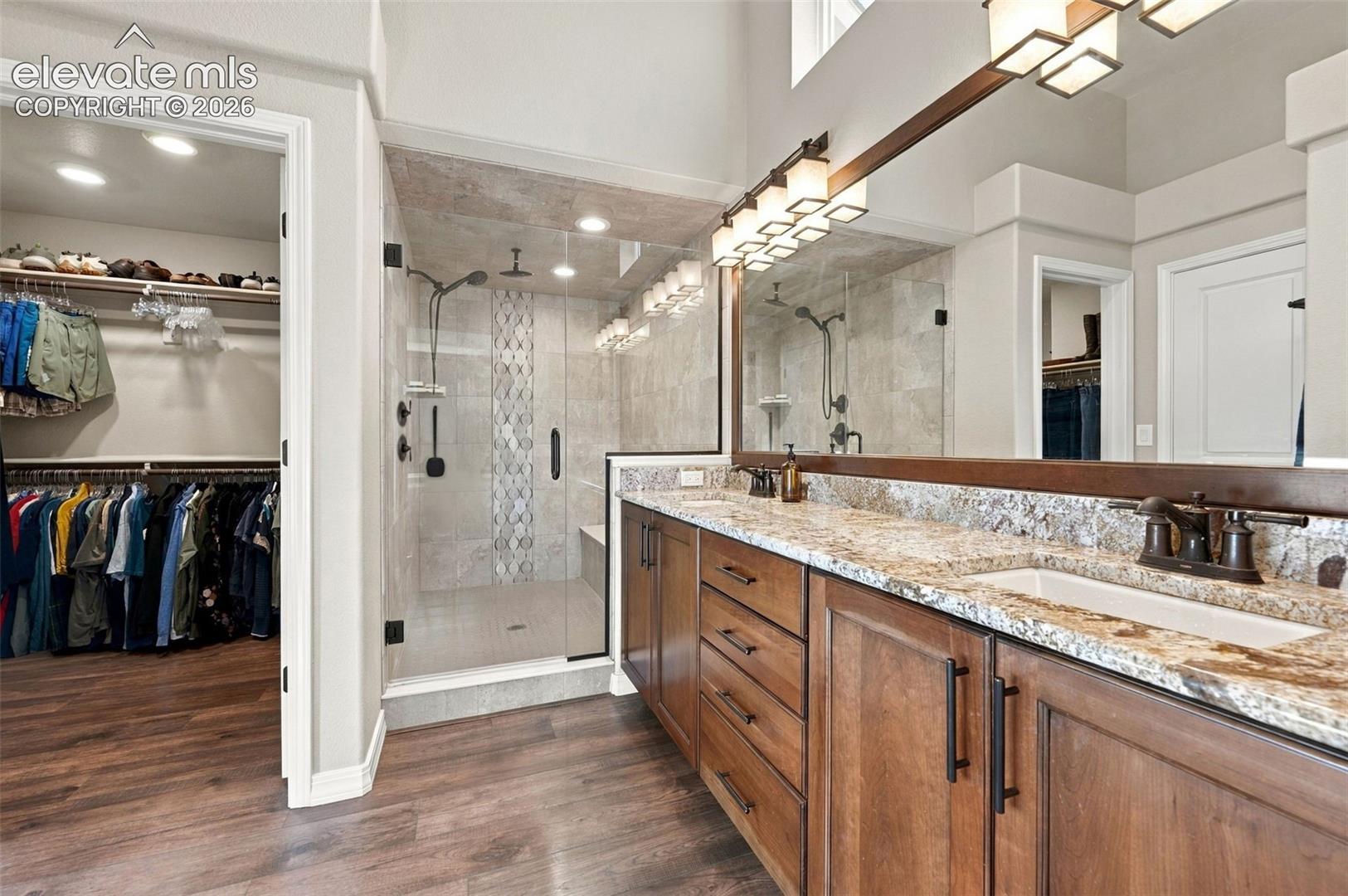 Dual vanity with stone countertops, wood cabinetry, and rectangular undermount sinks