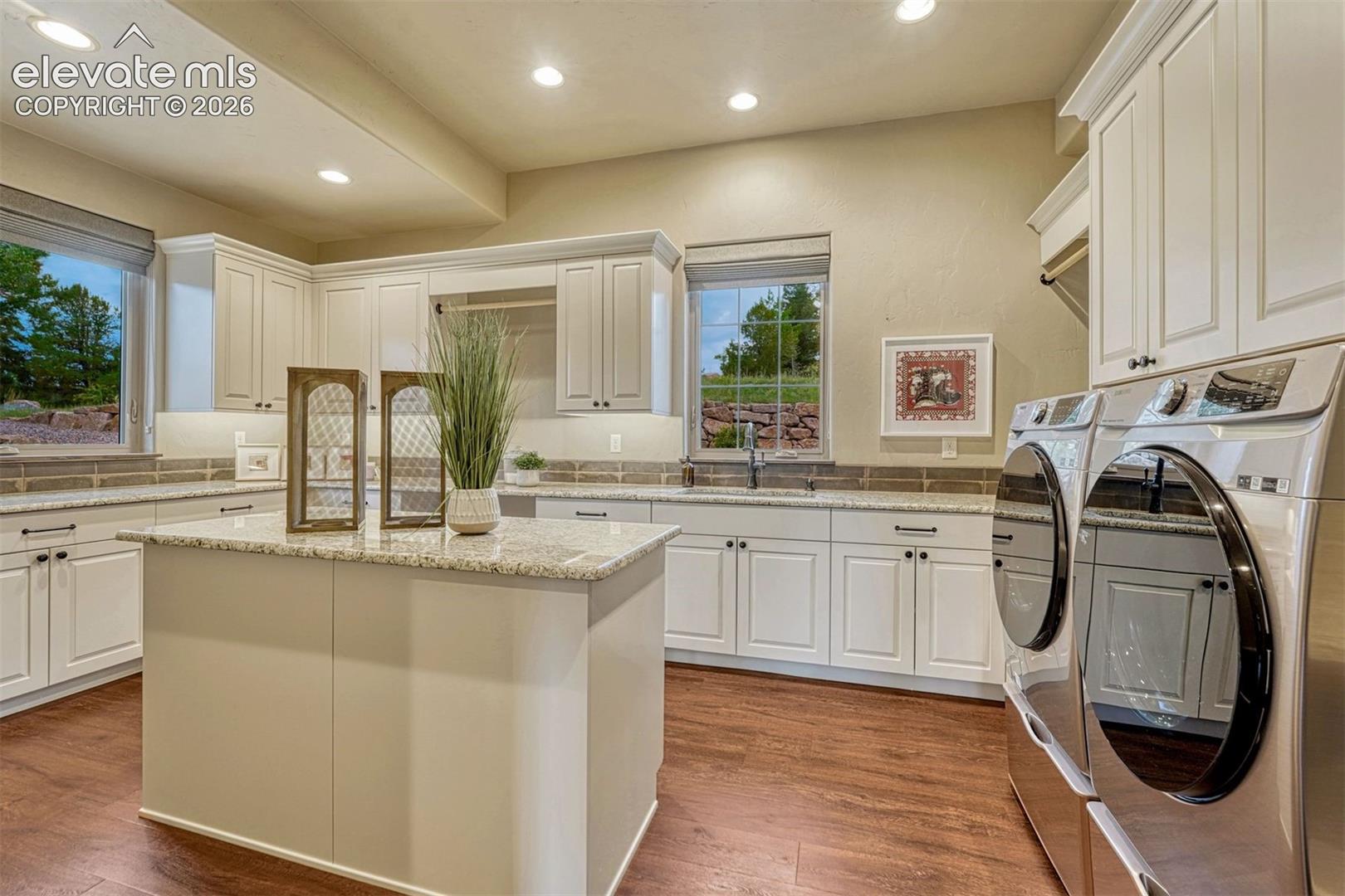 White cabinetry with black hardware, granite countertops, wood-finish flooring, and recessed lighting