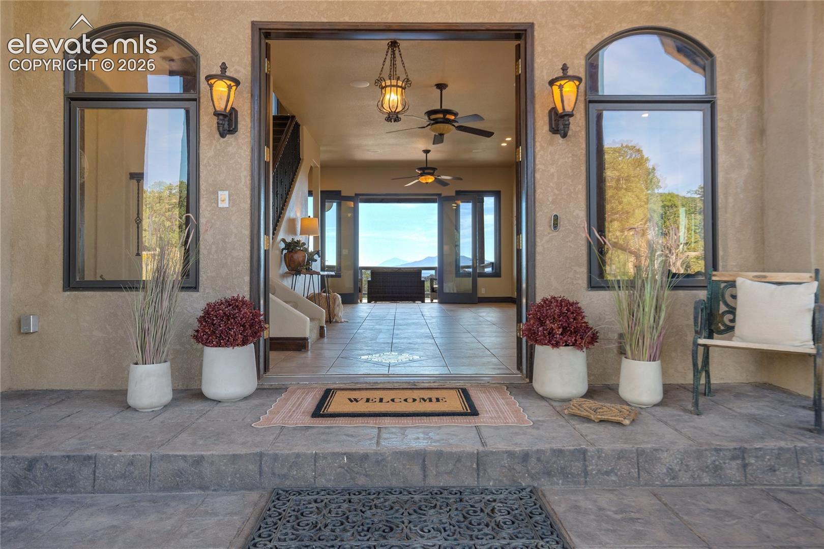 Stucco exterior with arched windows, exterior sconce lighting, and a stone-look entryway