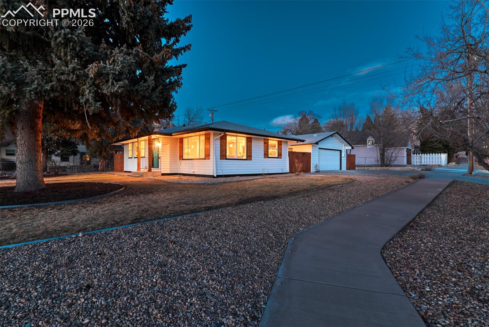 Single story home featuring a garage, driveway, and an outdoor structure