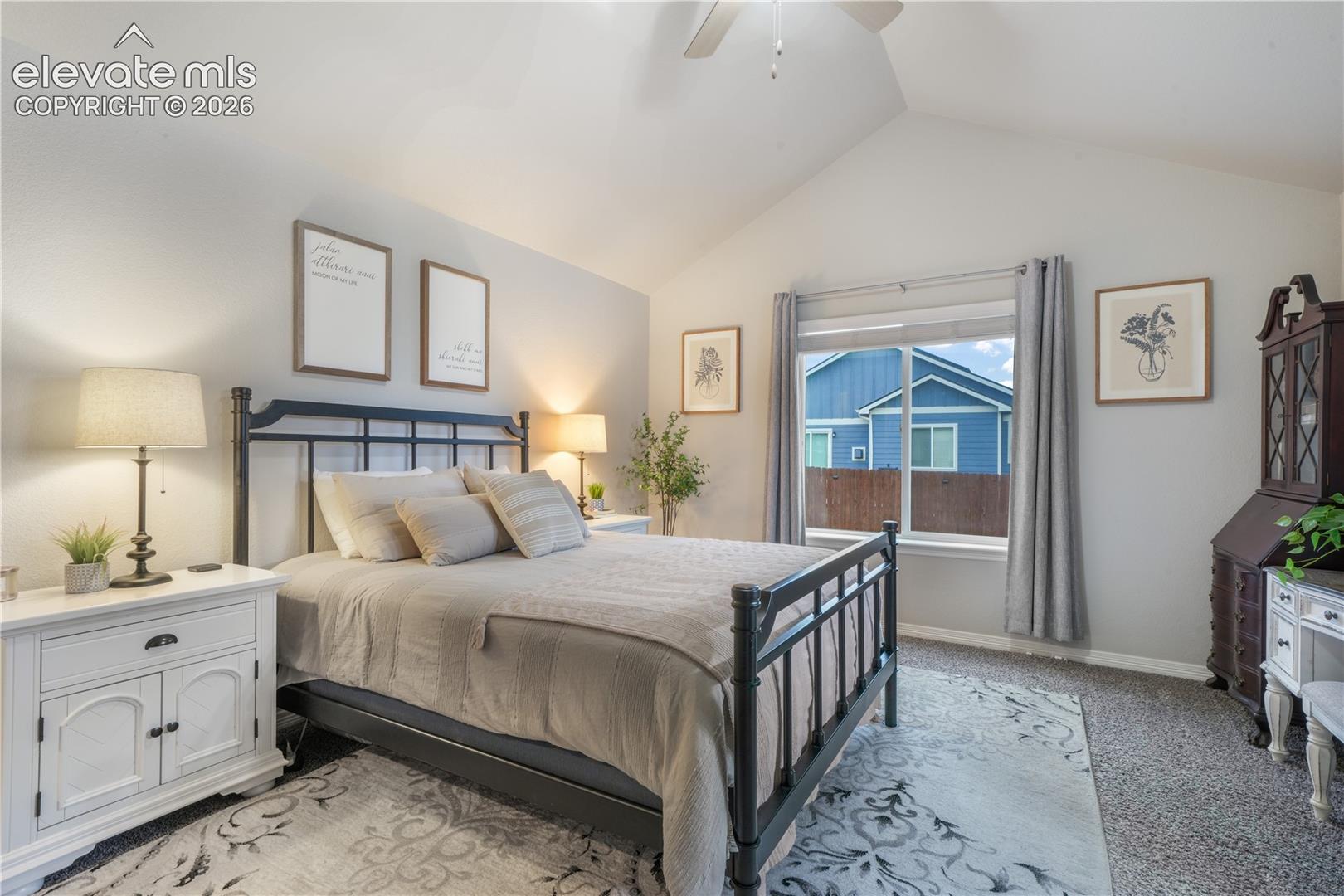 Vaulted ceiling, ceiling fan, carpeting, window with curtains, and gray wall paint