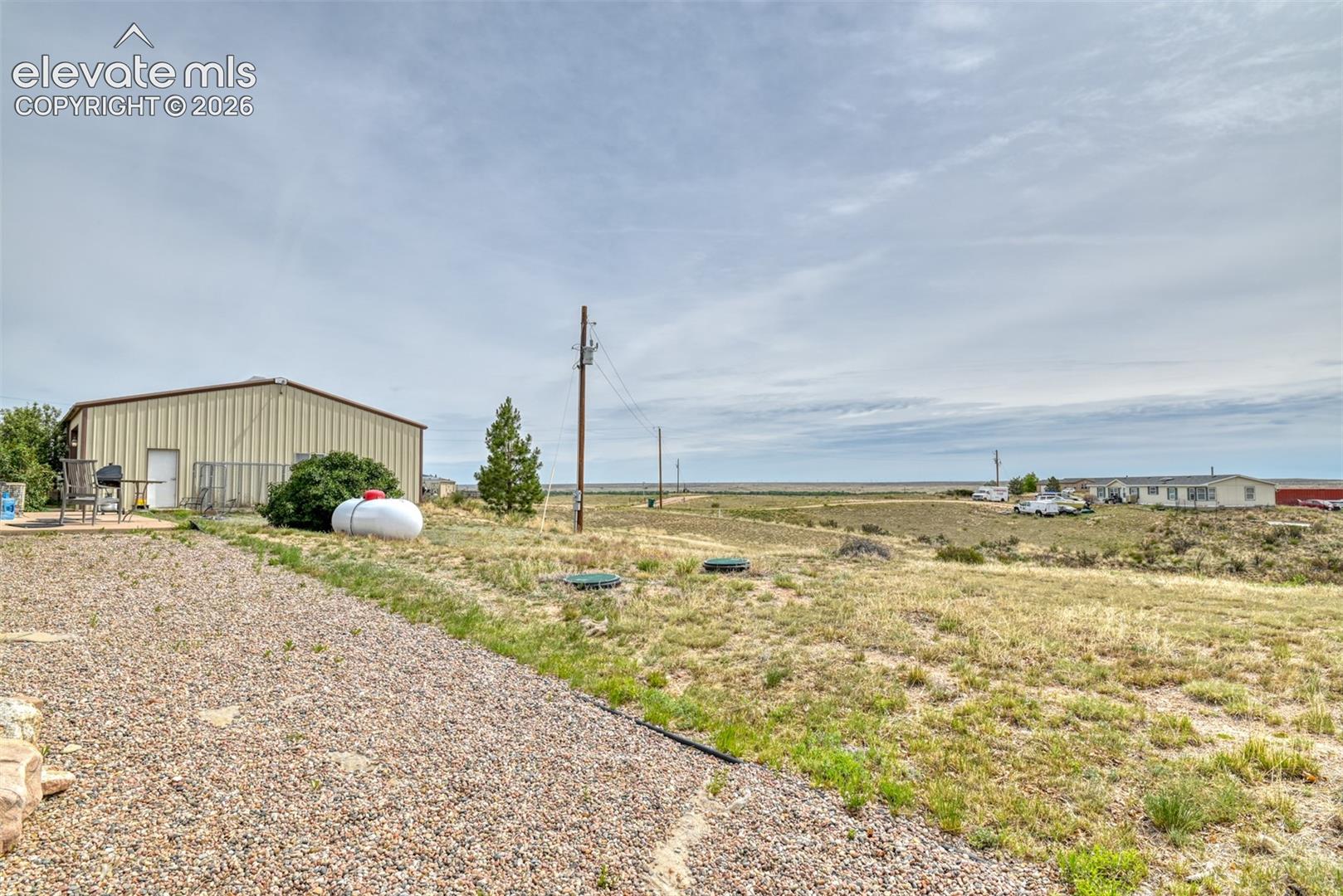 Metal-sided outbuilding with multiple entry points and a gravel driveway