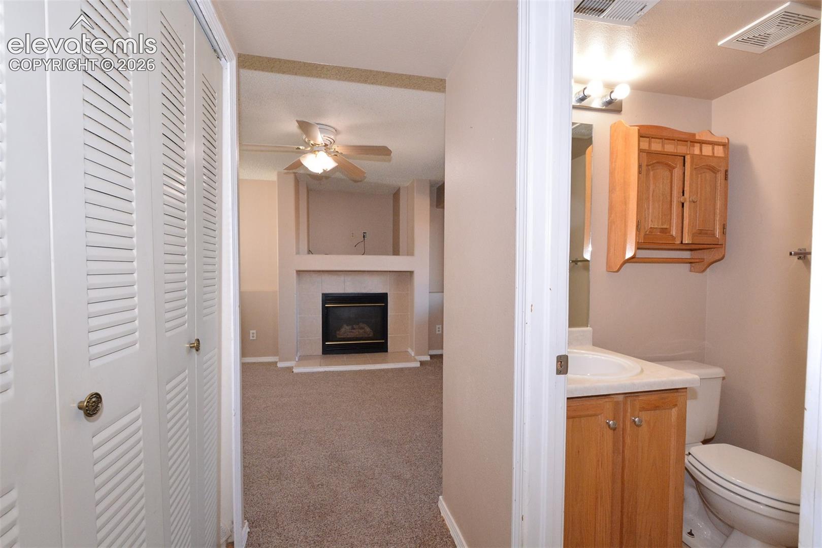 Living space featuring a fireplace with a tiled surround, vaulted ceiling, and ceiling fan