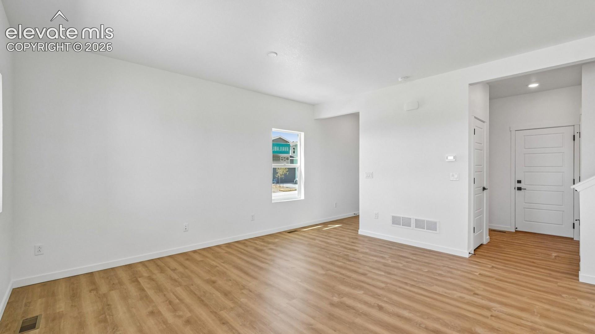 Neutral interior space featuring wood-finish flooring, recessed lighting, and a multi-panel exterior entry door