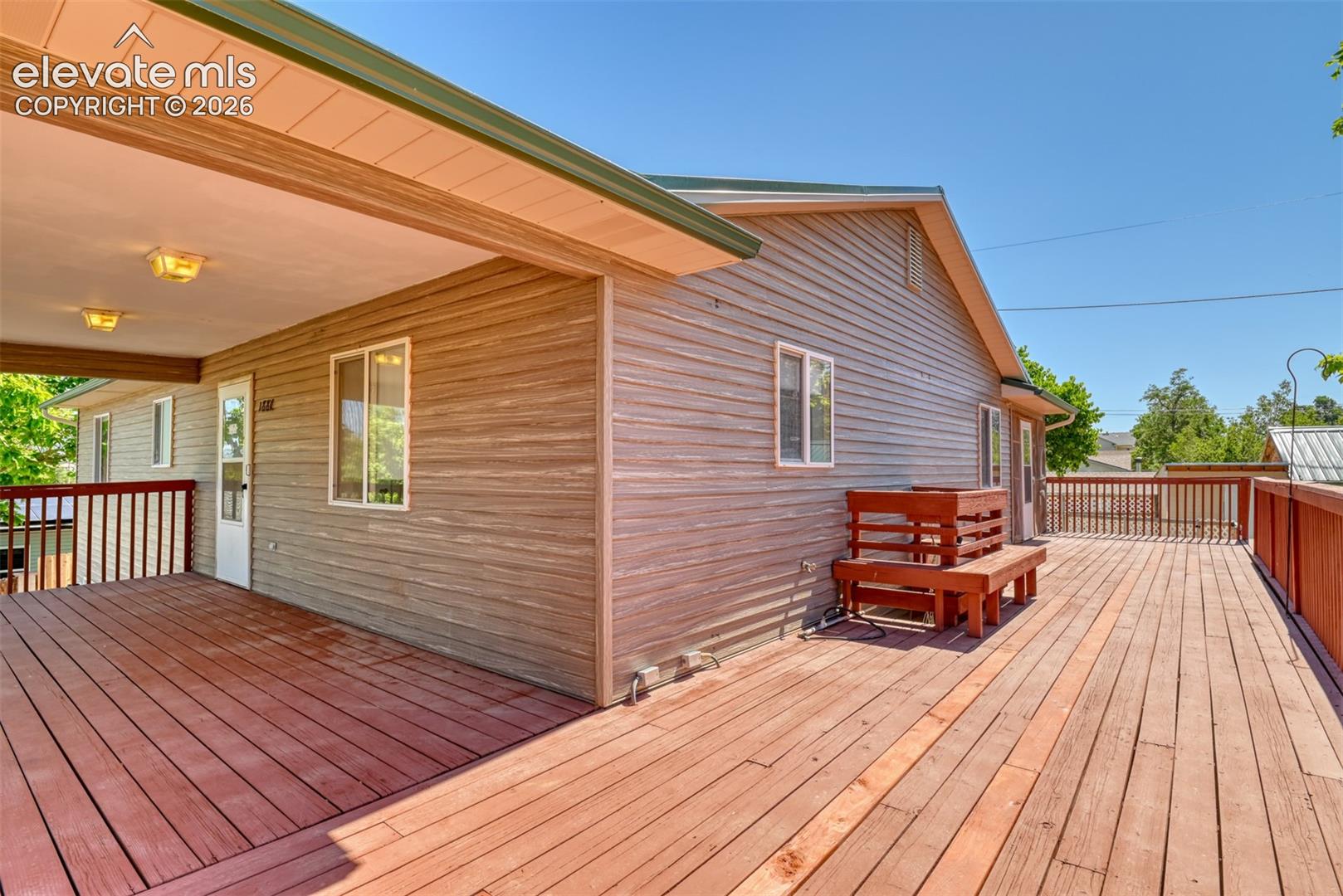 Expansive wood-plank deck featuring a covered area with recessed lighting and built-in railing