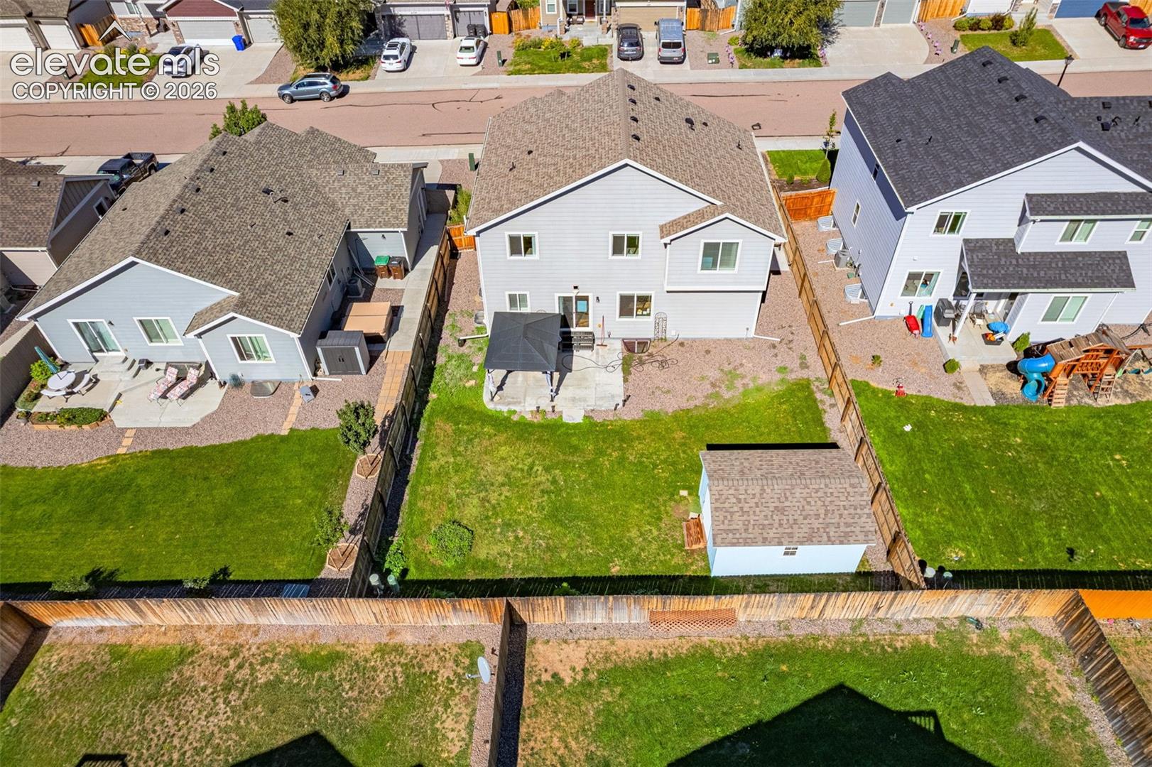 Expansive backyard featuring a manicured lawn, established privacy fencing, and a built-in storage shed