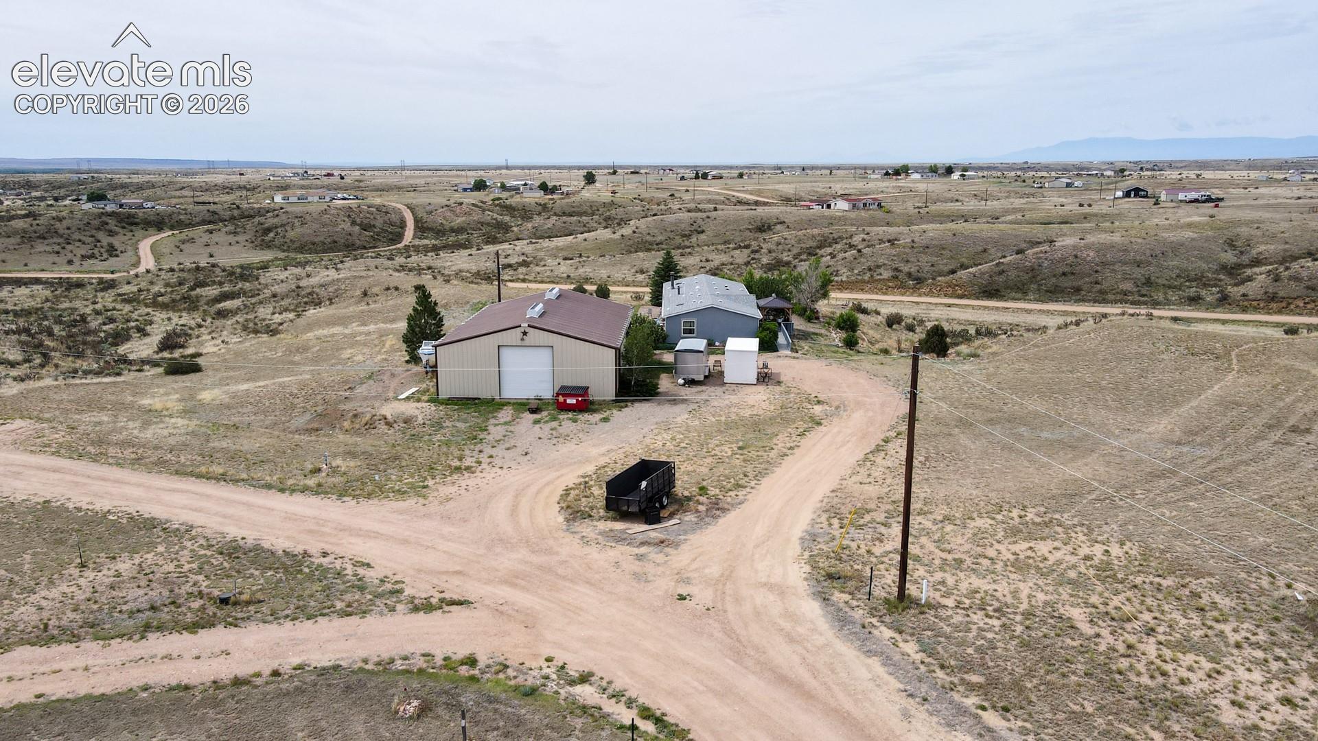 Expansive rural property featuring a main residence, an outbuilding with a large garage door, and a utility shed