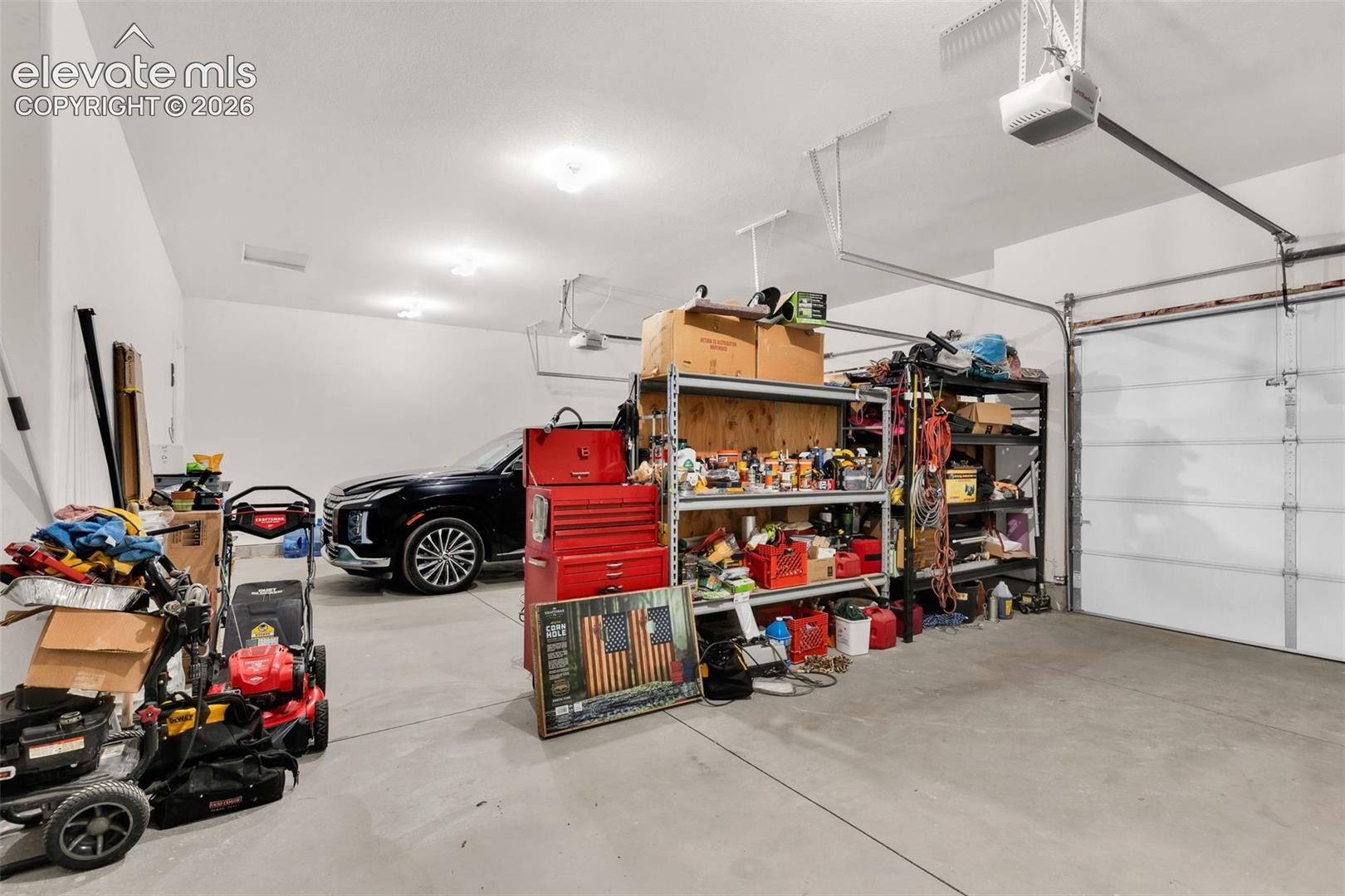 Spacious garage with light grey concrete flooring and white painted walls