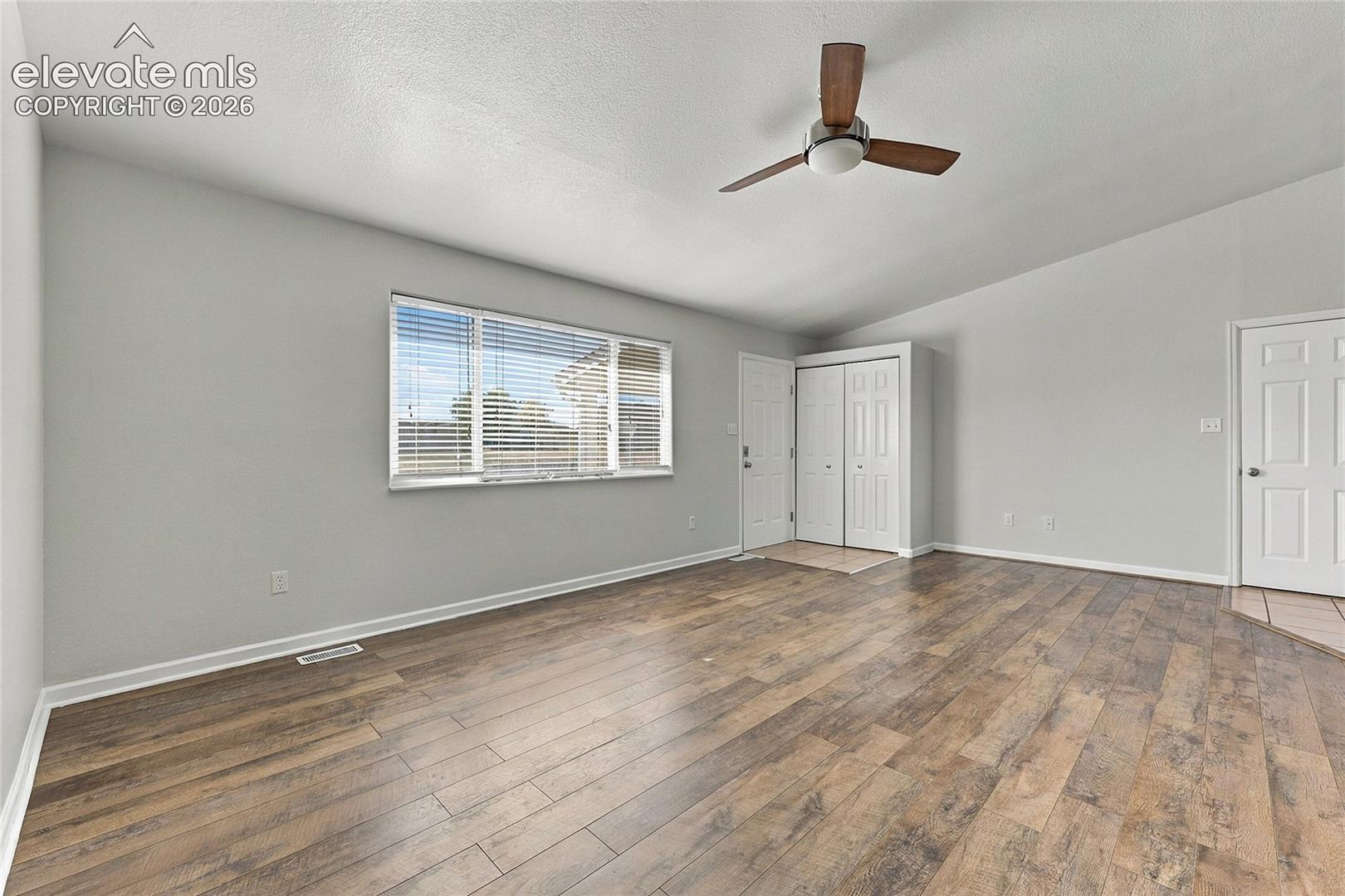 Vaulted ceilings, wood-finish flooring, ceiling fan, and multi-panel doors