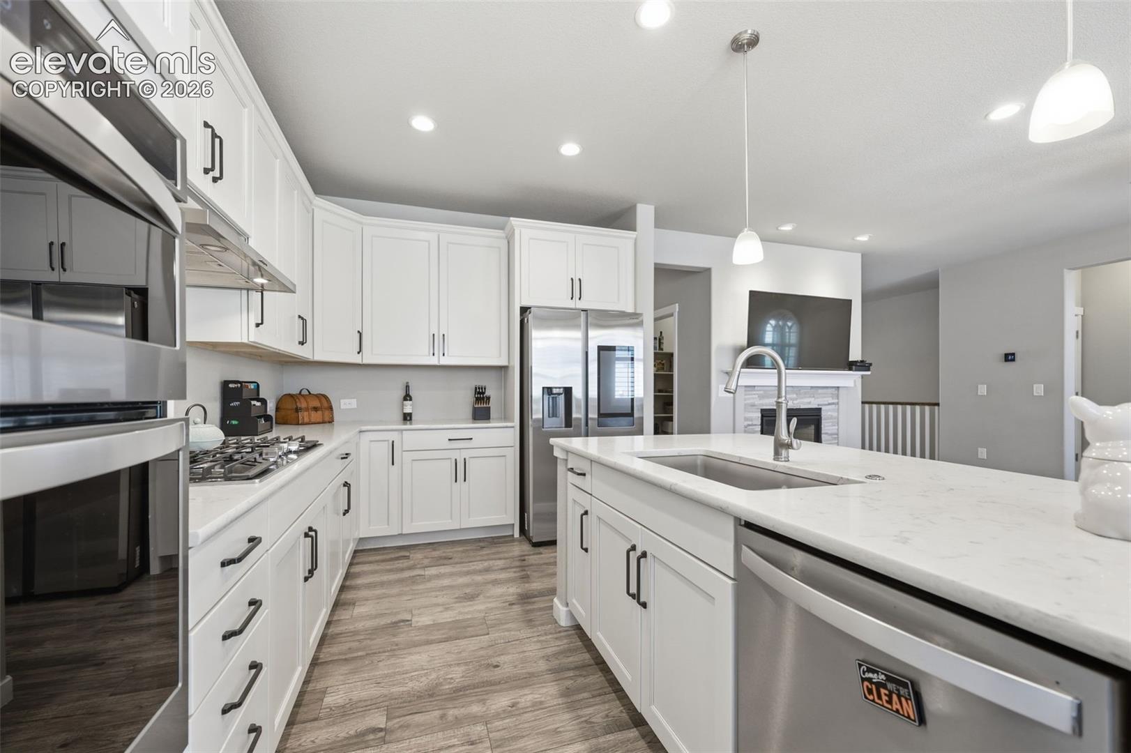 Kitchen featuring white cabinetry, stainless steel appliances, light brown luxury vinyl plank flooring, and recessed lighting.