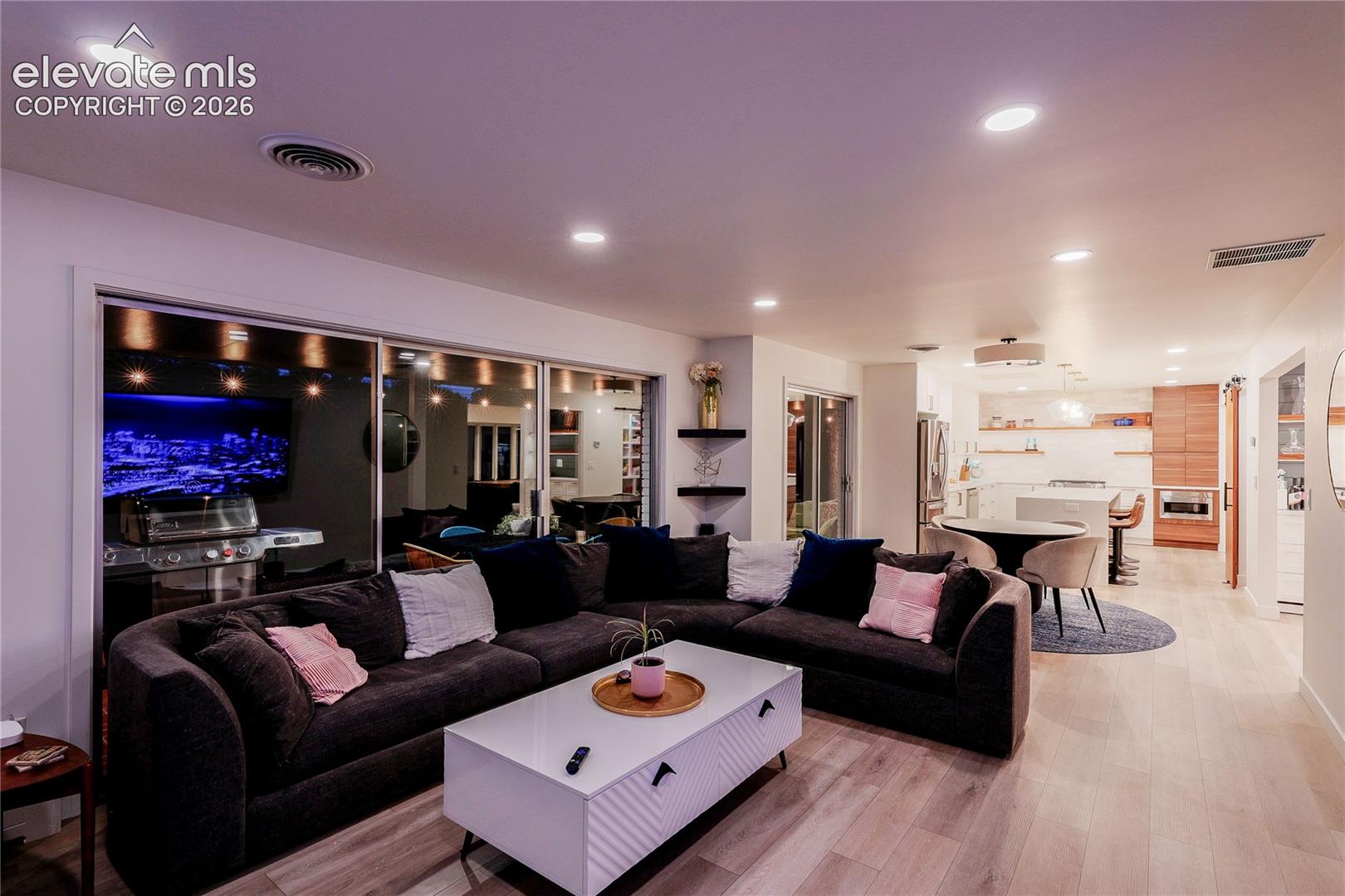 Recessed ceiling lighting, wood-finish flooring, sliding glass doors, built-in shelving, and a built-in kitchen island