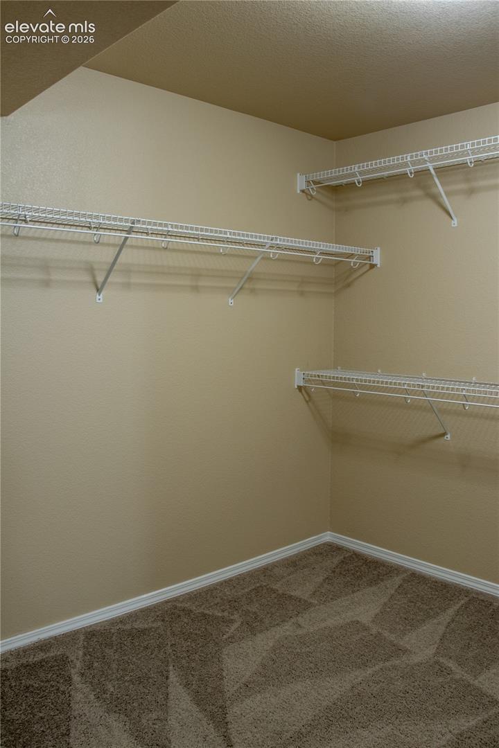 Walk-in closet with wire shelving, neutral-toned walls, and patterned carpeting