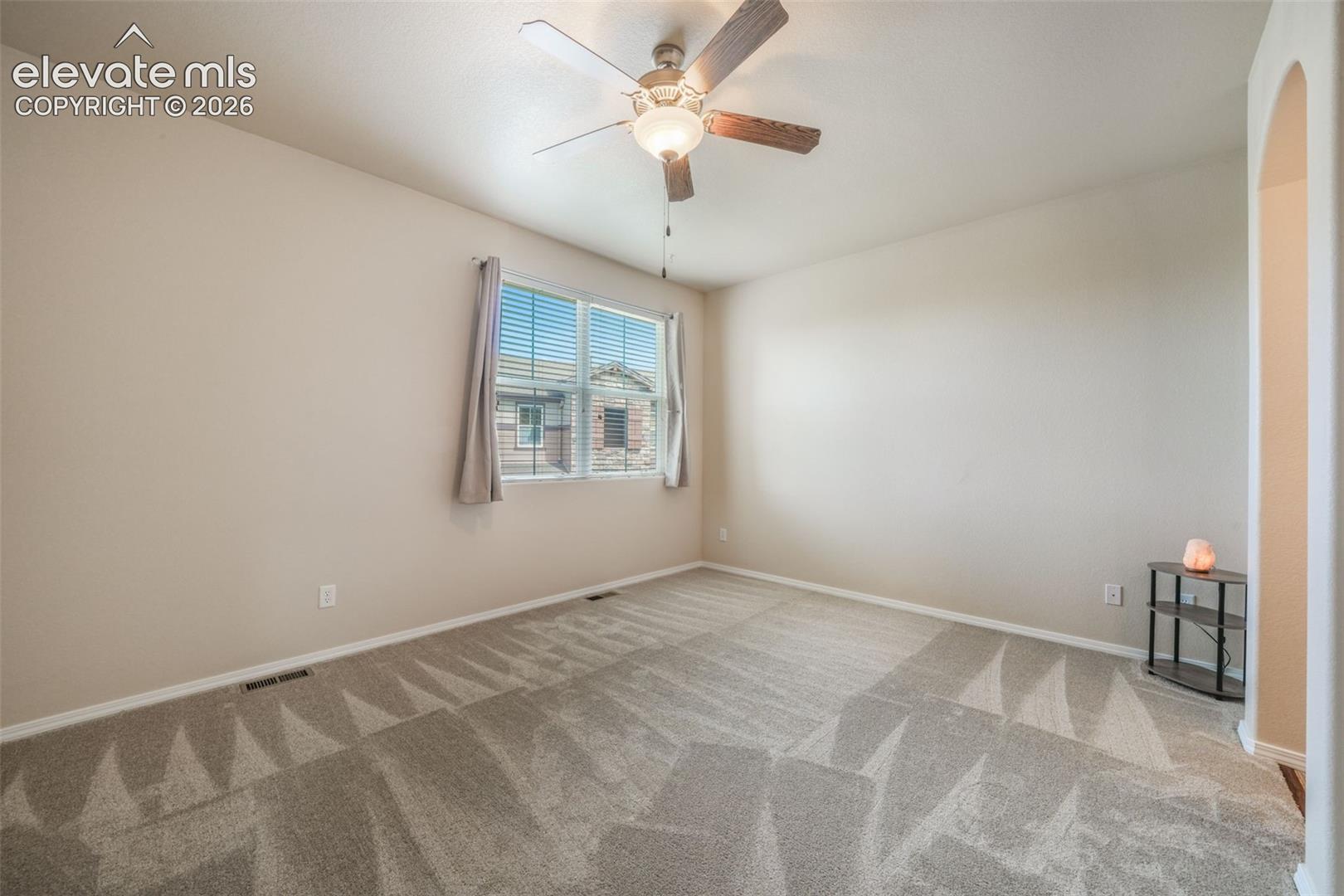 Recessed window with blinds, ceiling fan with integrated lighting, arched entryway, and neutral-toned wall paint